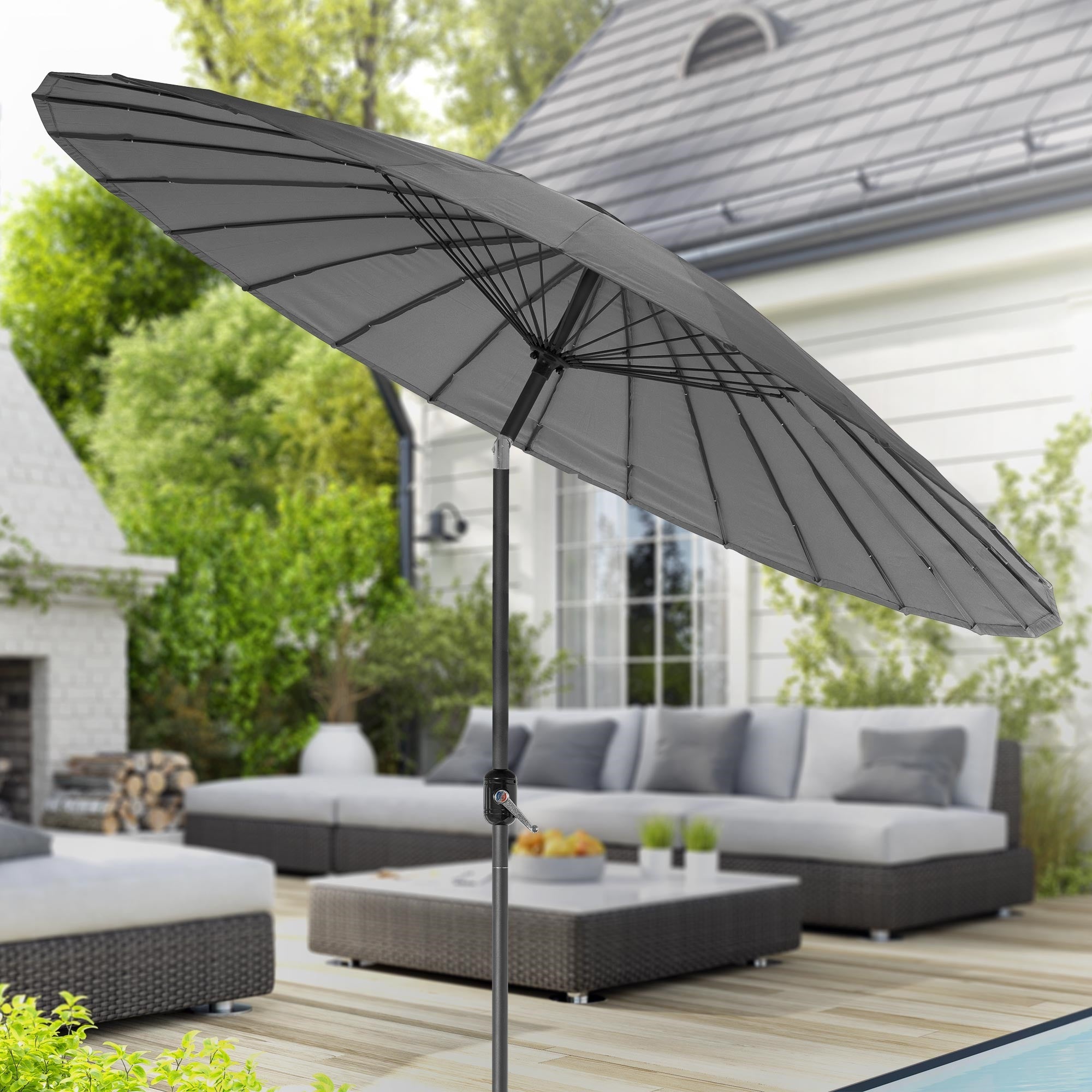 Vue du jardin avec un parasol gris et un coin salon confortable.
