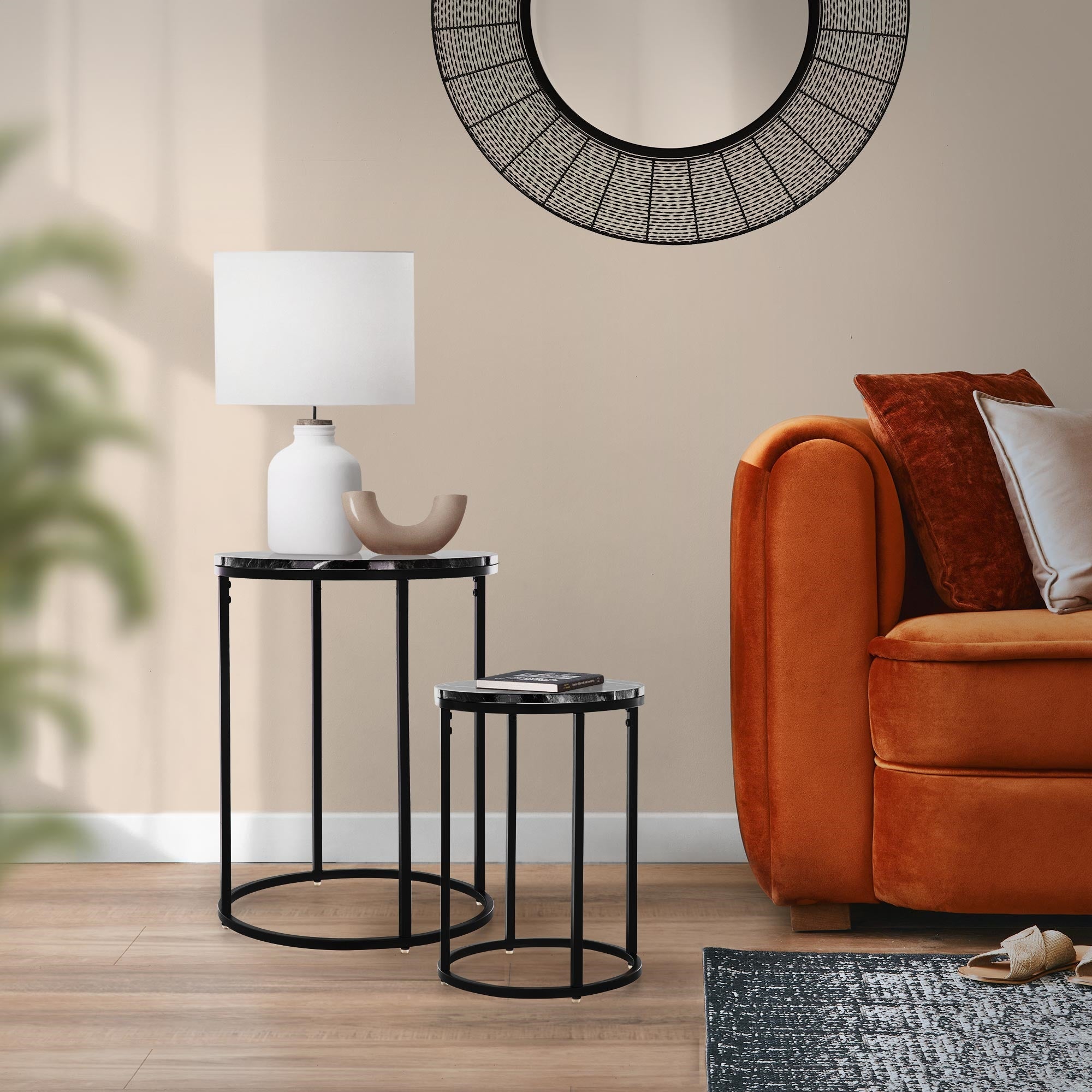 Et stue med en orange sofa, to borde og en lampe.