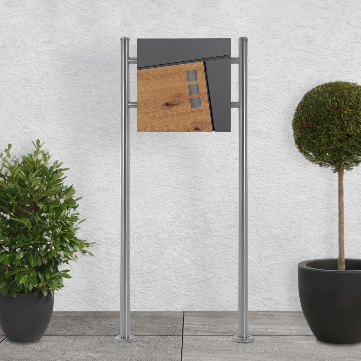 Mailbox on a stand, surrounded by plants.