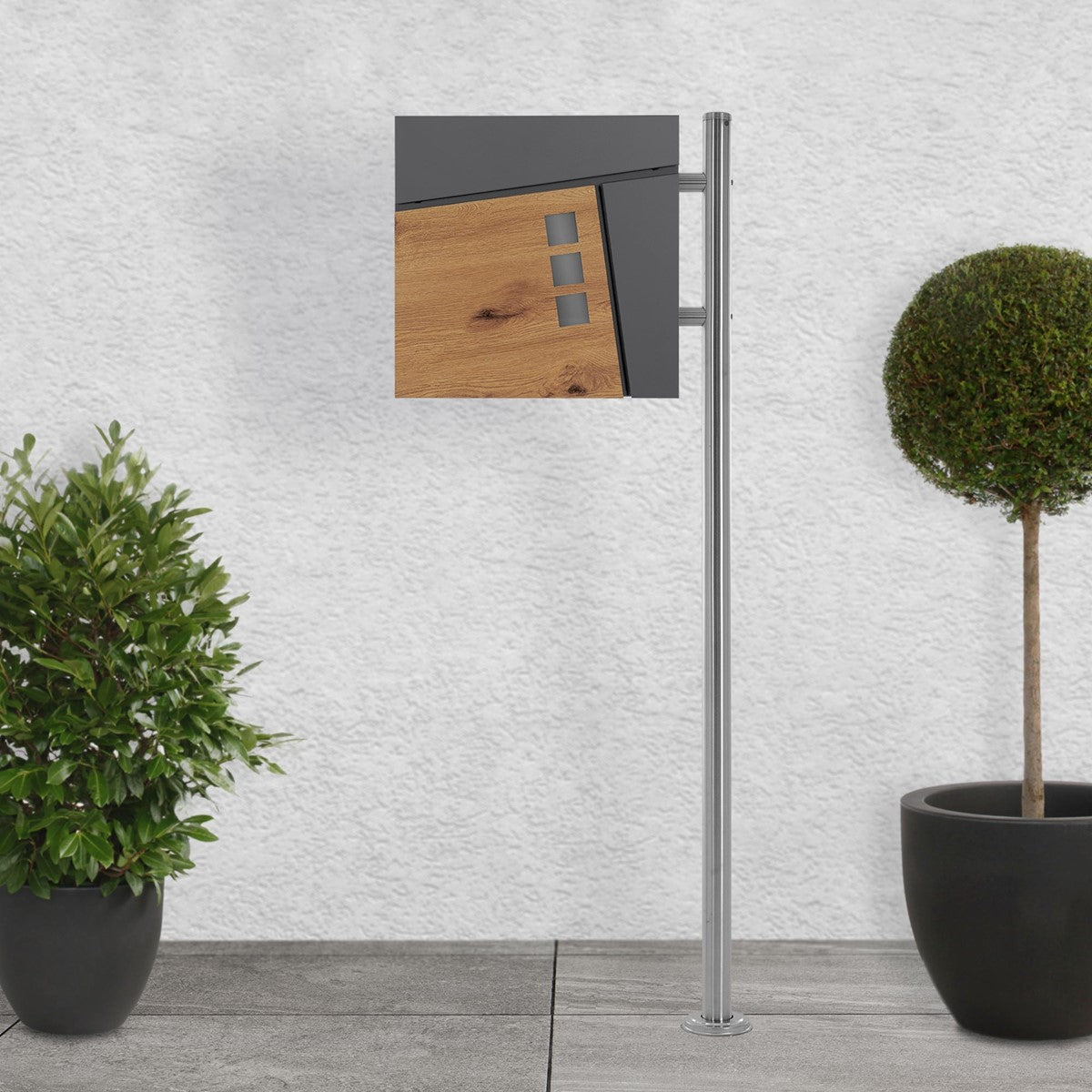 Mailbox with a wood and metal finish, surrounded by two plants.