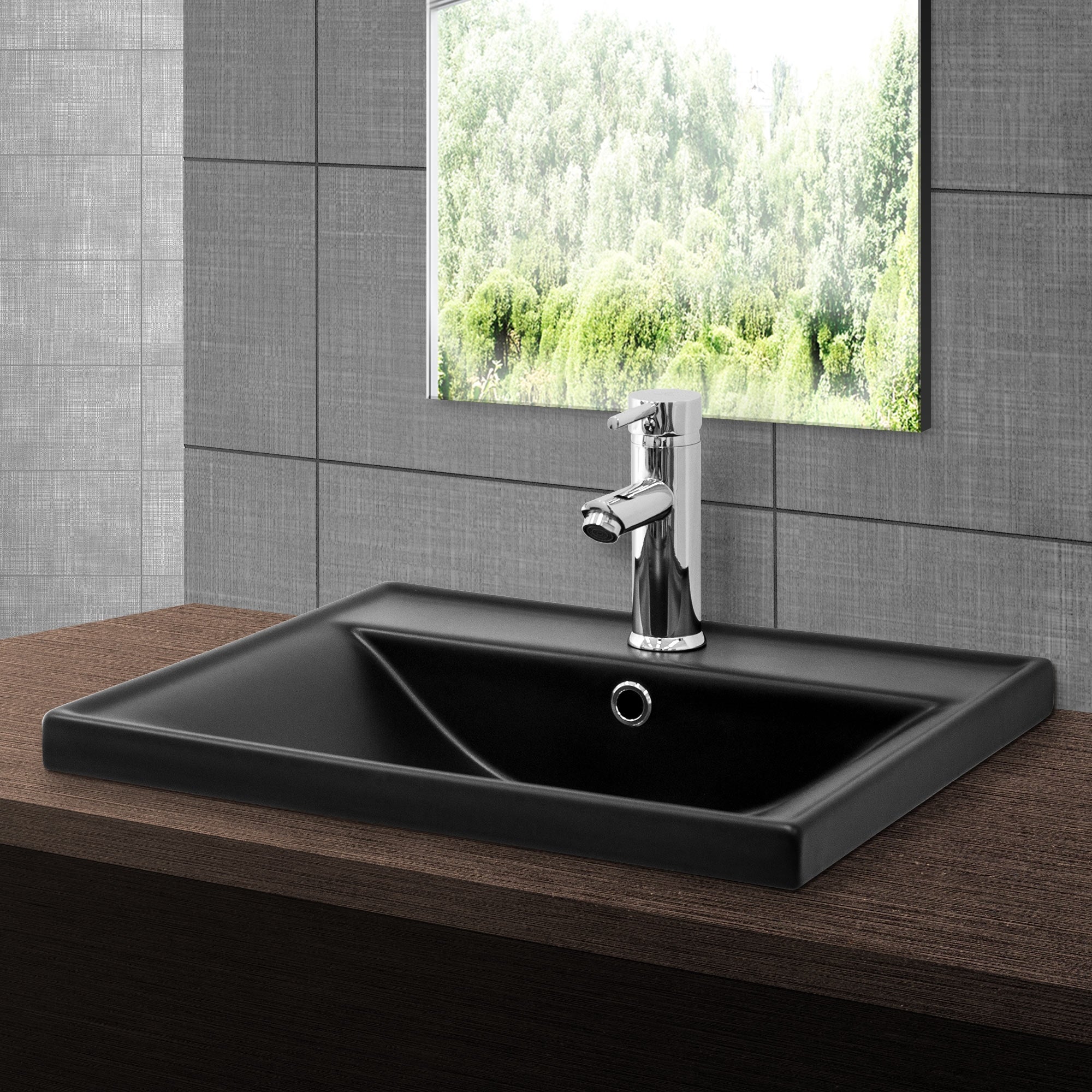 Black sink with faucet in front of a window overlooking trees.