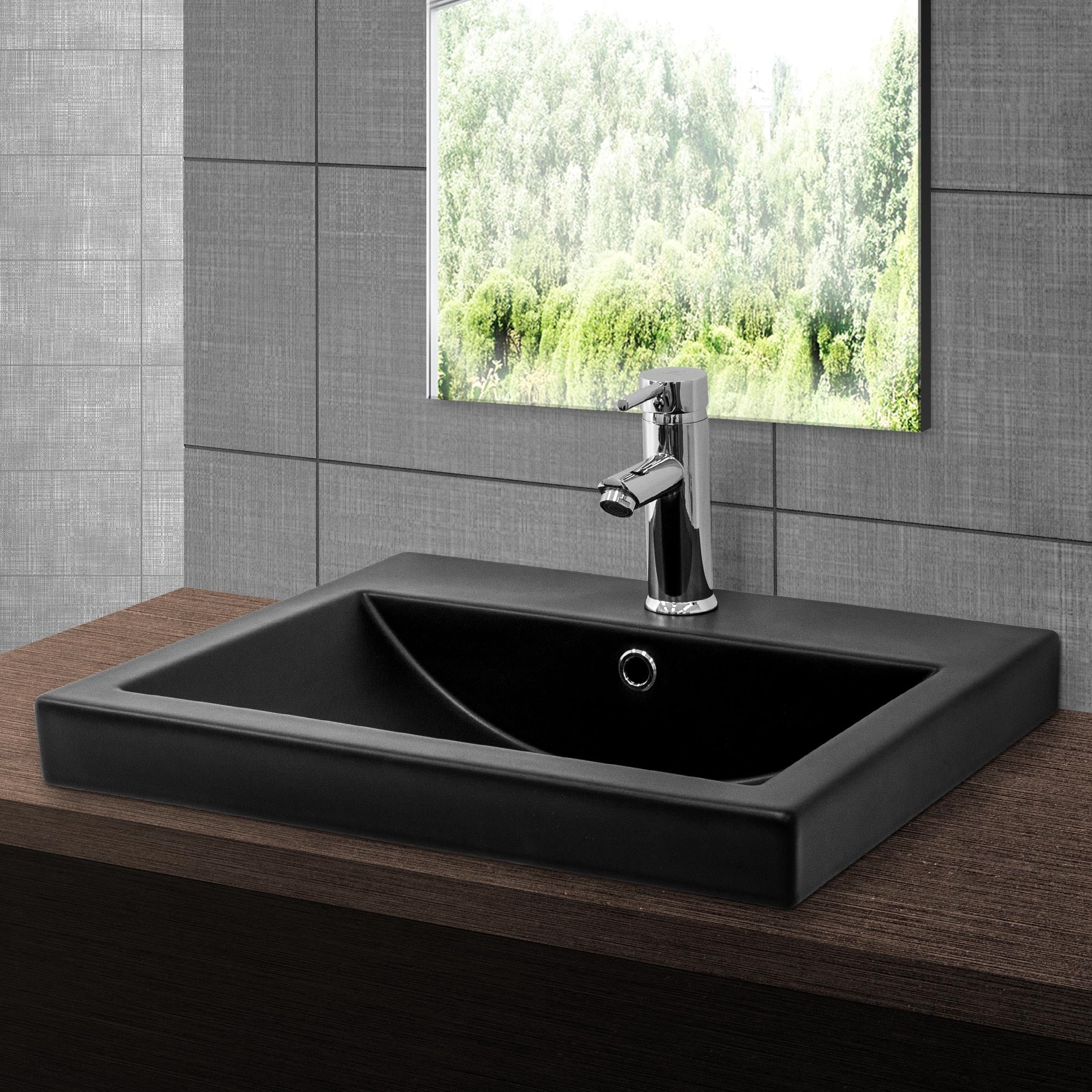 Black sink with faucet in front of a window overlooking trees.