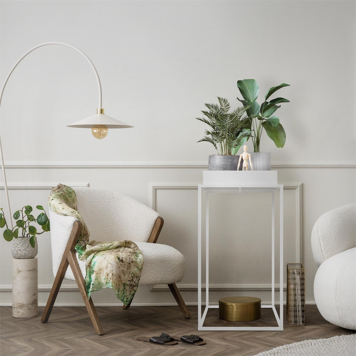 Zona de estar com um suporte para flores branco, plantas e um cadeirão.