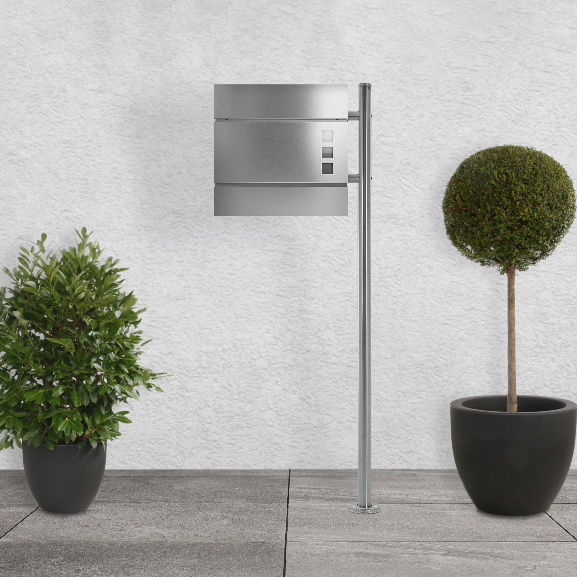 Soporte de buzón de metal con un buzón y dos plantas en macetas.