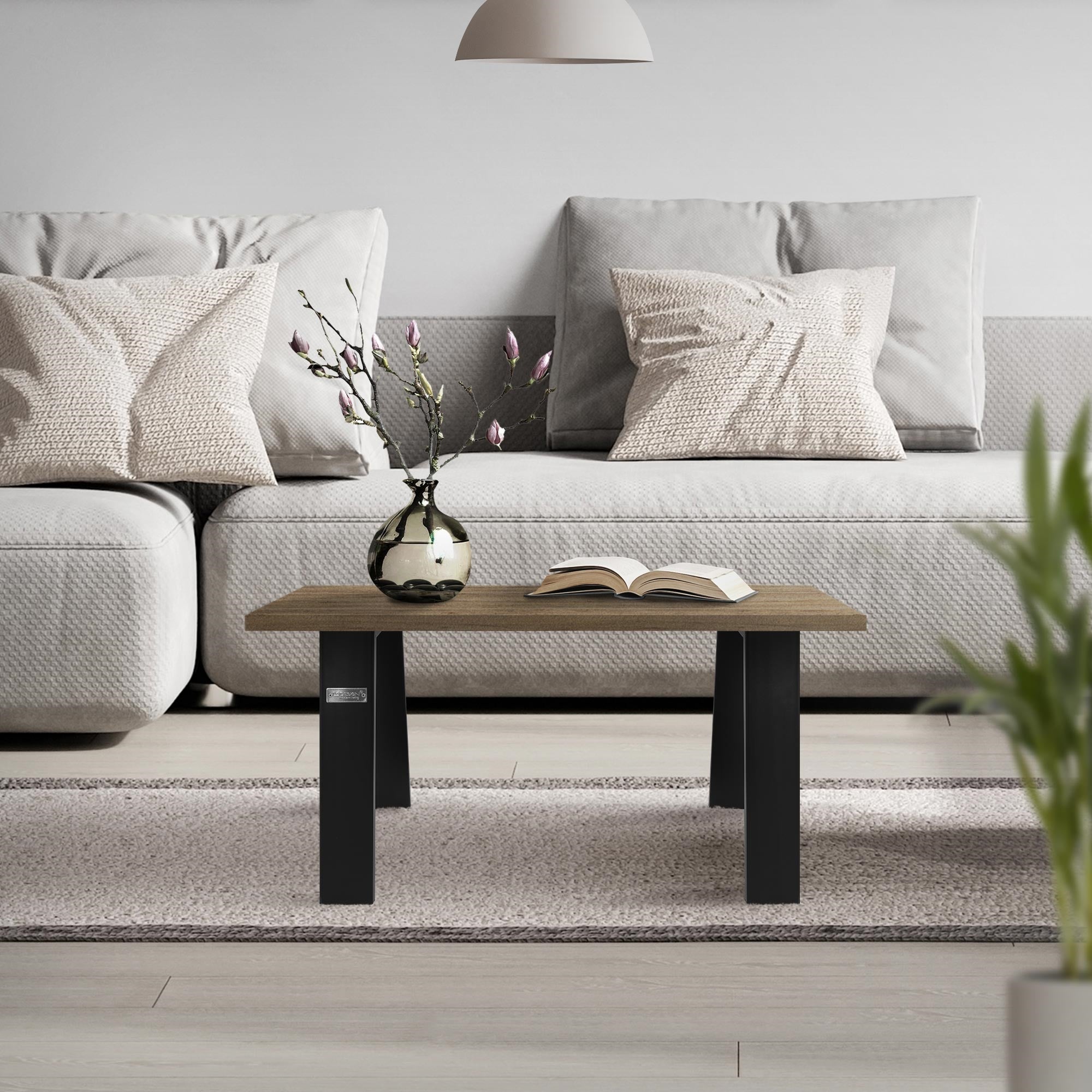 Et stue med en grå sofa, et sofabord og en vase med grene.
