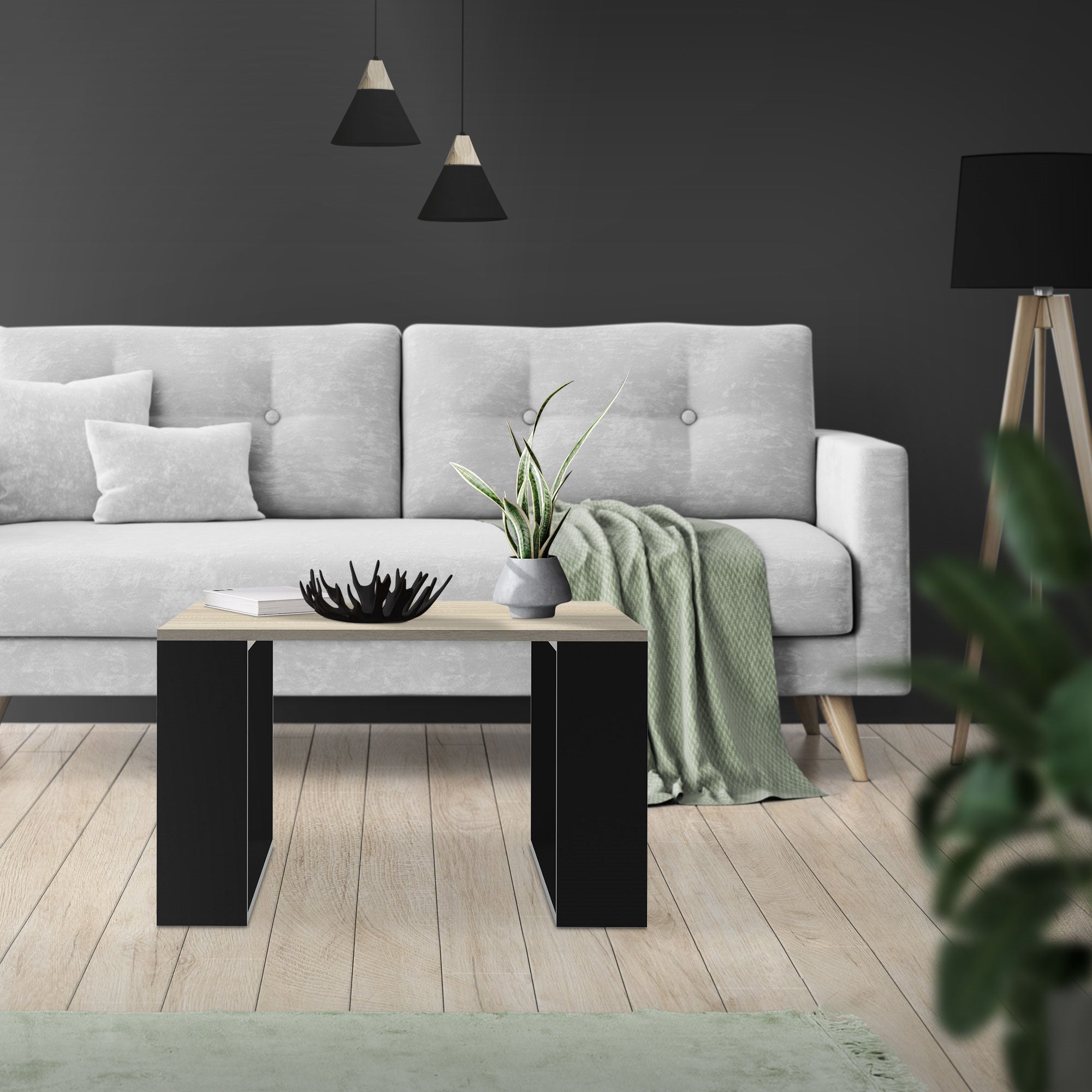 Lys stue med grå sofa, bord og planter på gulvet.