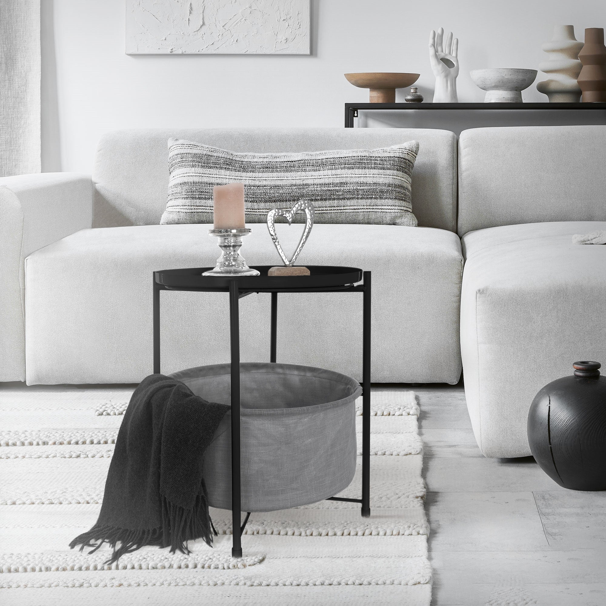 Black table with gray bag, on a light sofa and carpet in a living room.