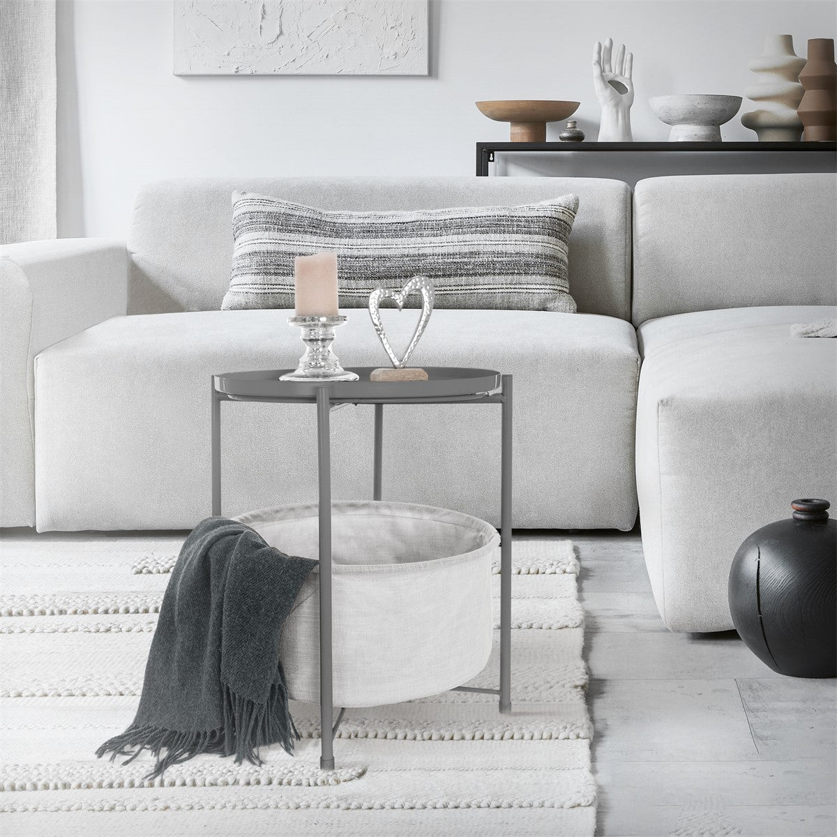 Wohnzimmer mit grauem Sofa, Tisch und Dekoration auf dem Tisch.