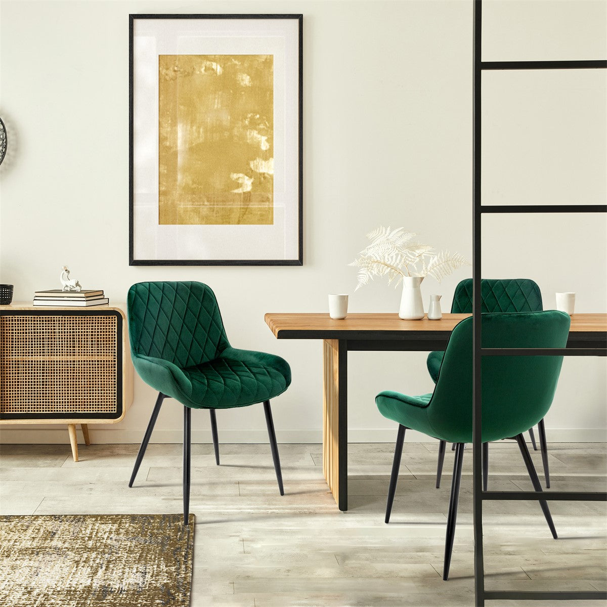 Sala de jantar com cadeiras verdes, uma mesa e um quadro dourado na parede.