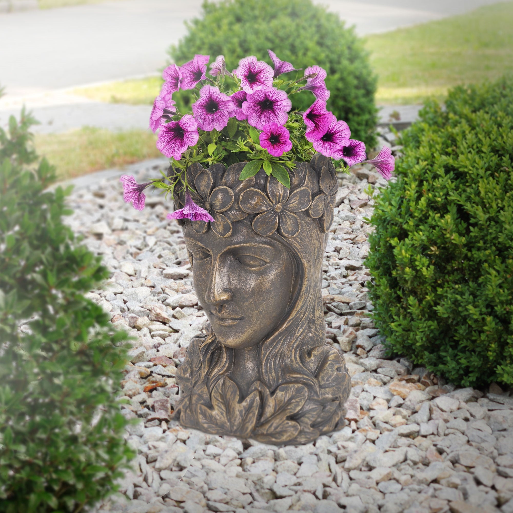 Buddha-Kopf-Pflanztopf im Garten mit blühenden Petunien.