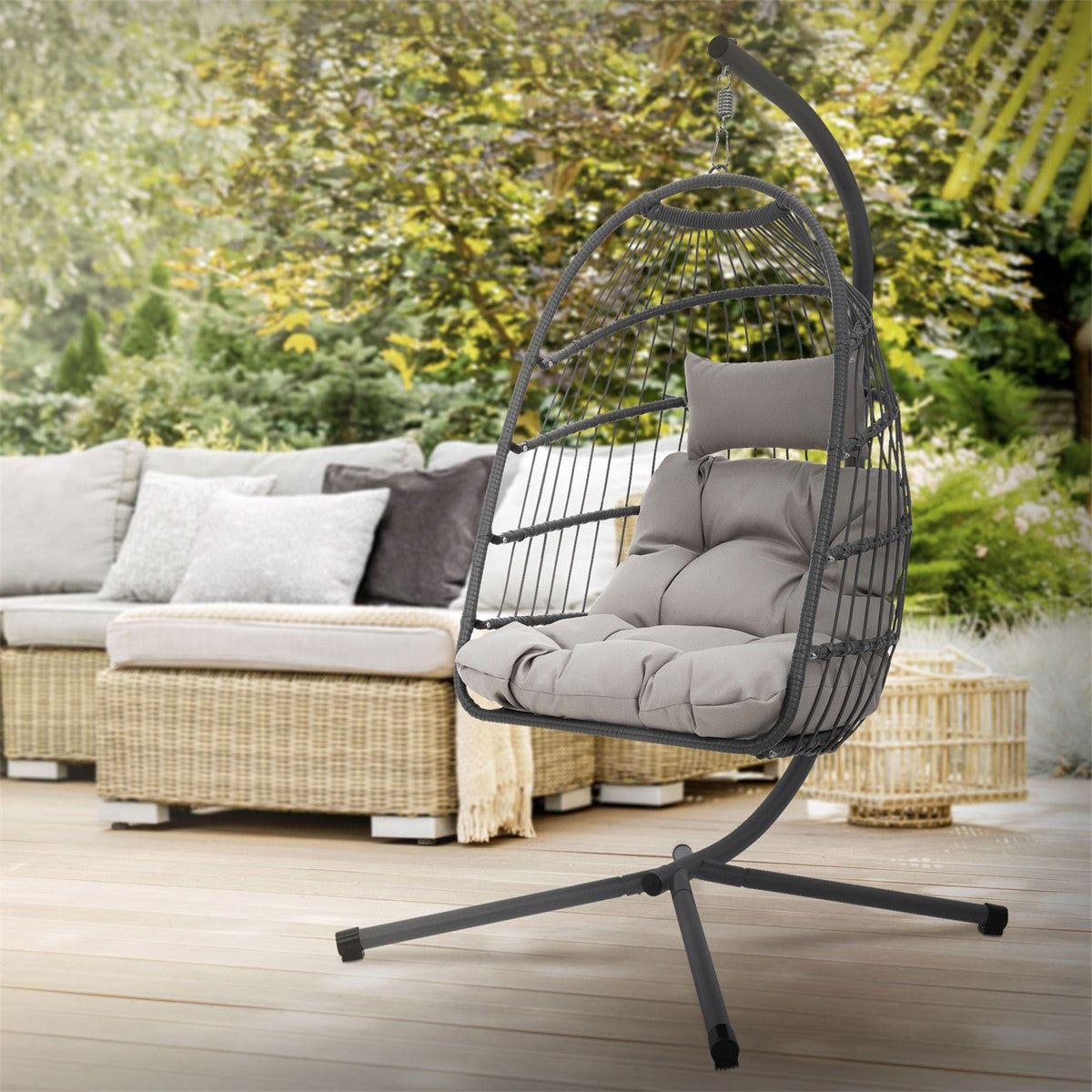 Hängender Sessel auf einer Terrasse mit Pflanzen und einer Couch im Hintergrund.