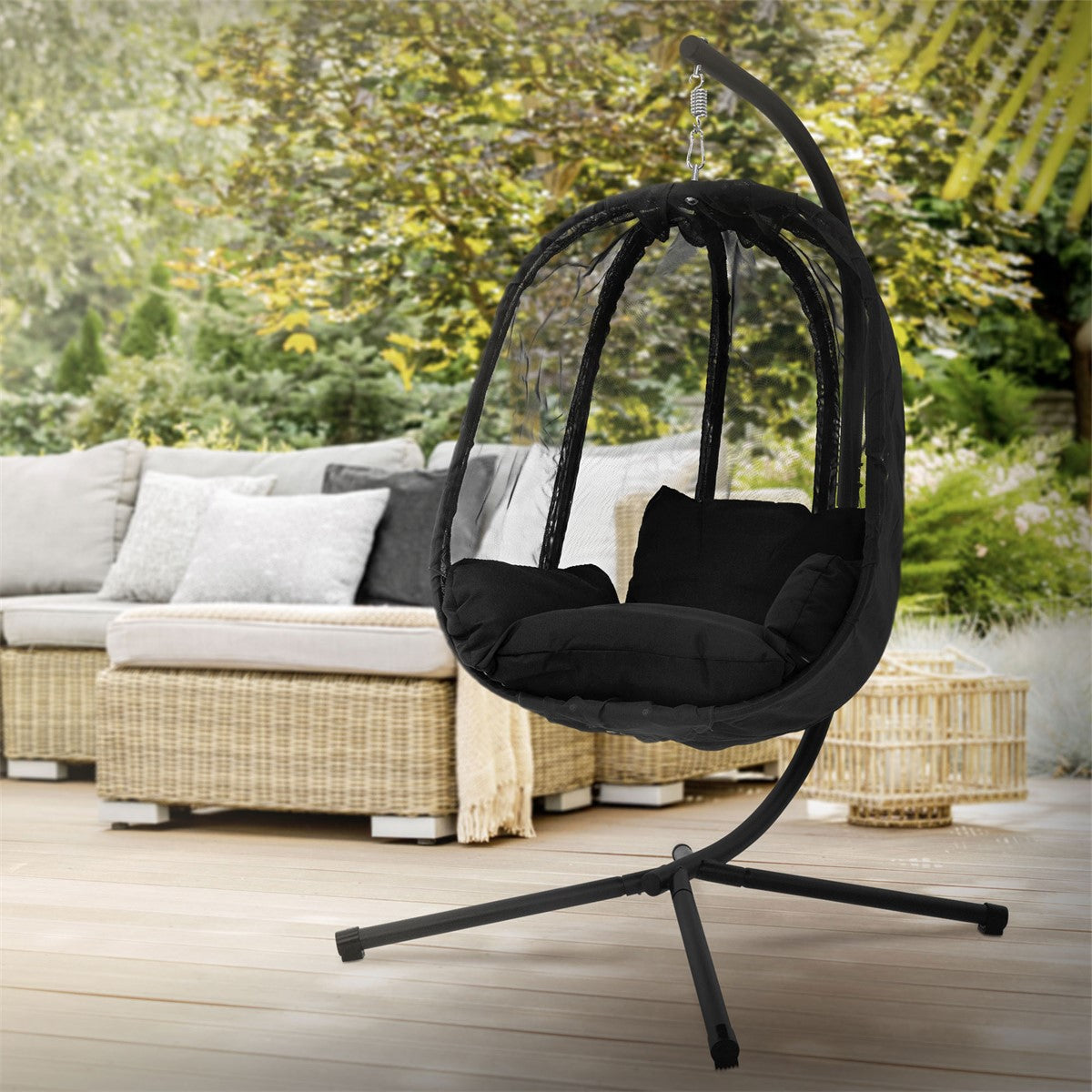 Hängesessel im Freien auf einer Terrasse mit Sofa im Hintergrund.