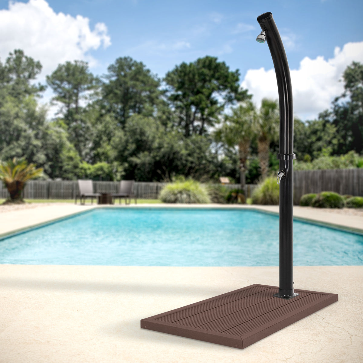 Rubinetto della doccia accanto a una piscina con lettini sullo sfondo.