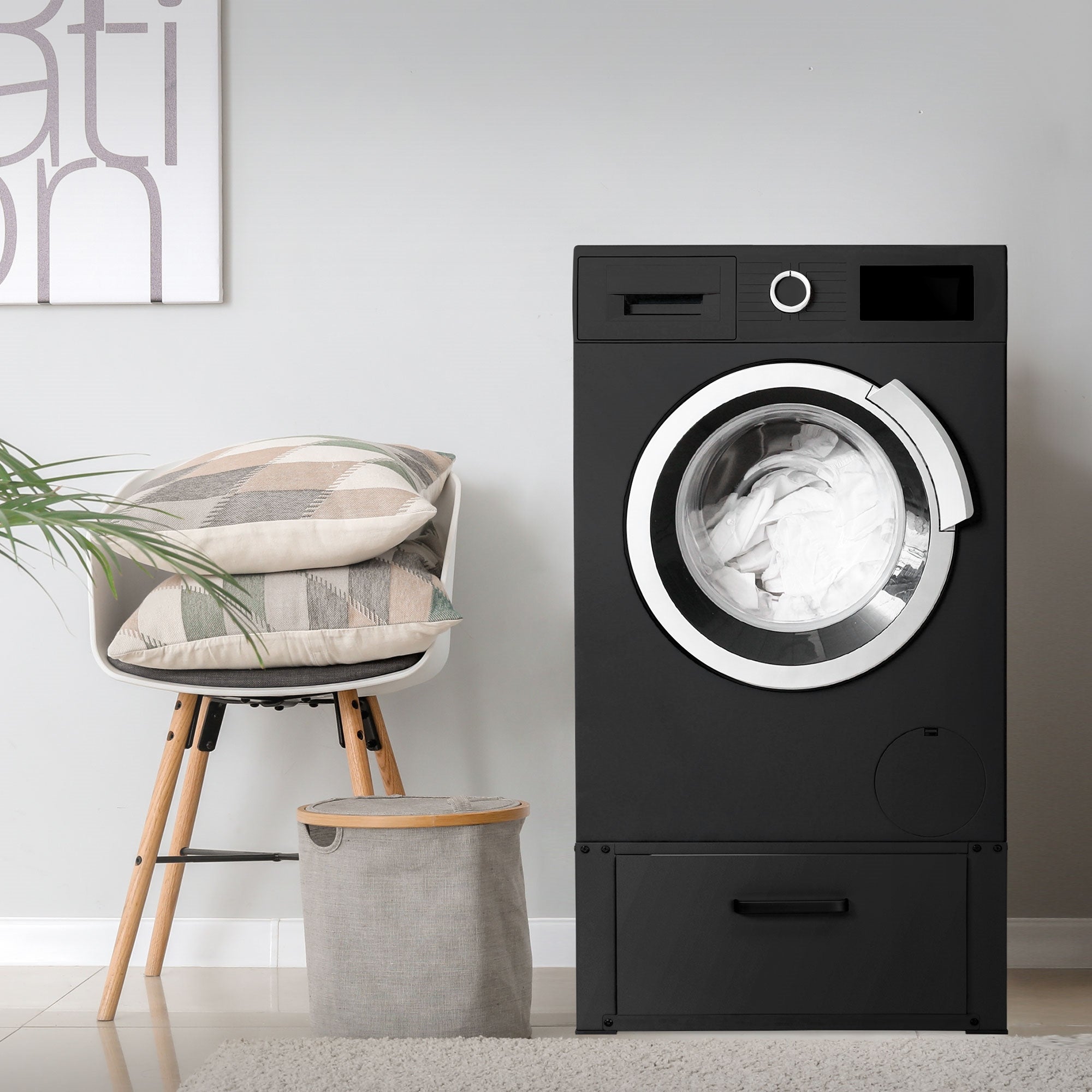 Lave-linge noir à côté d'une chaise et d'un panier à linge dans une pièce.