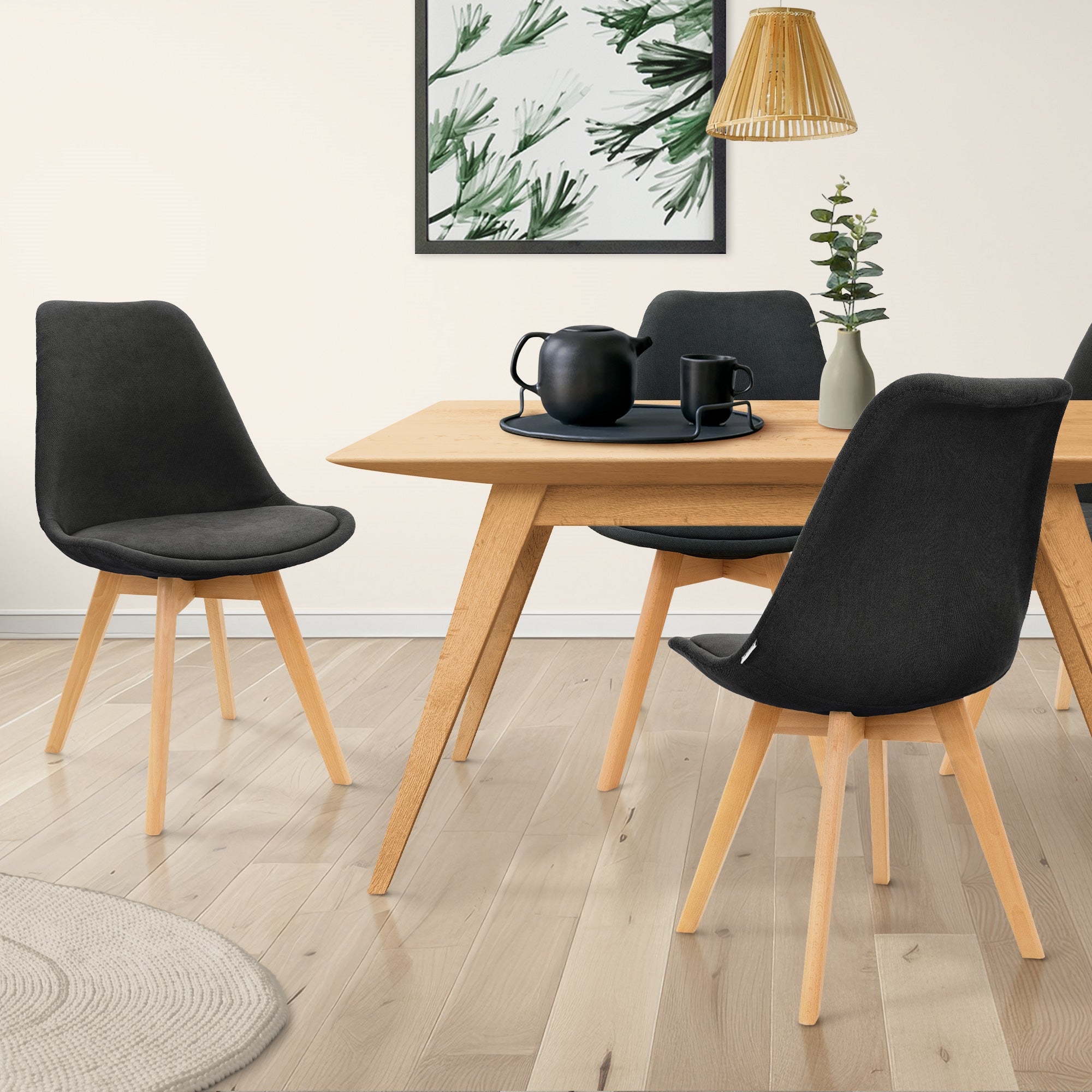 Ein Essbereich mit einem Holztisch, vier Stühlen und einer Pflanze im Hintergrund.