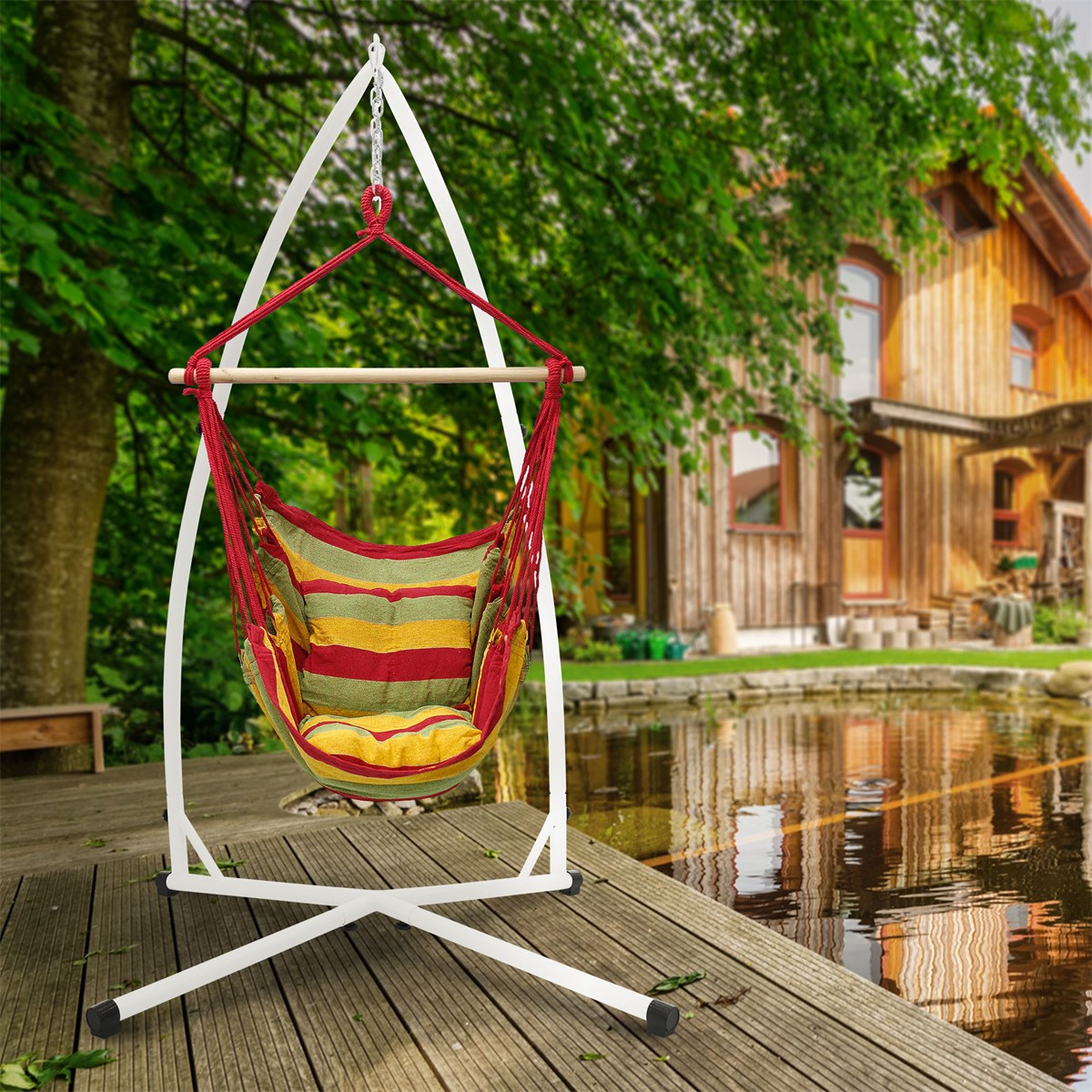 Hängesessel in rot mit Kissen, auf Holzdeck vor einem Haus und Wasser.