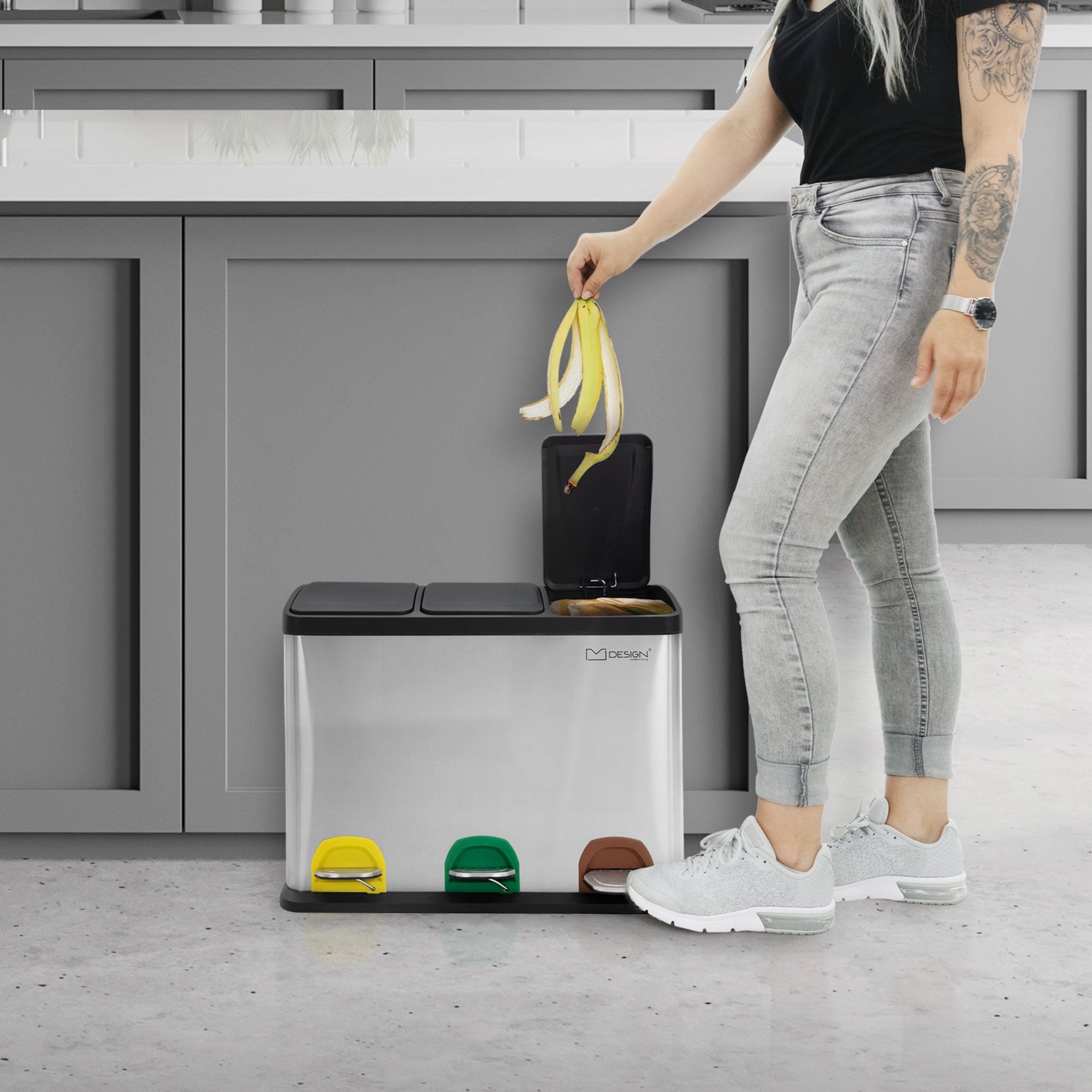 Person opens trash can with foot pedal in a modern kitchen.
