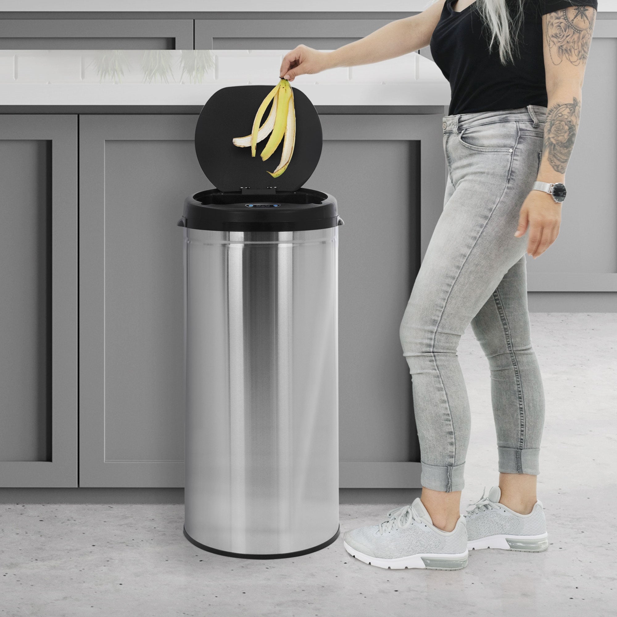 Person throws banana peel into trash can, lid is open.