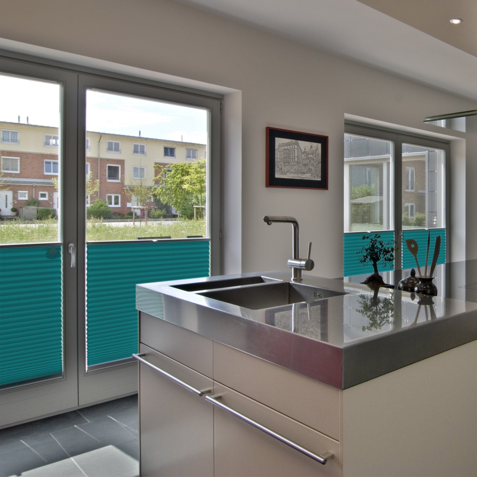 Cucina moderna con lavello in acciaio inox e grandi finestre.