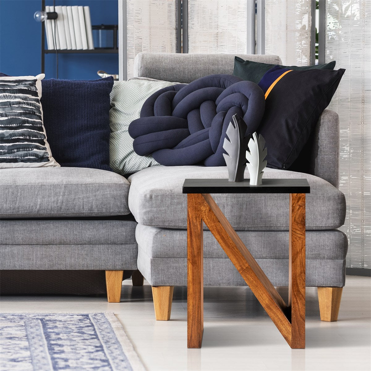 Grau gepolsterte Couch mit Kissen und einem kleinen Tisch mit Holzbeinen.