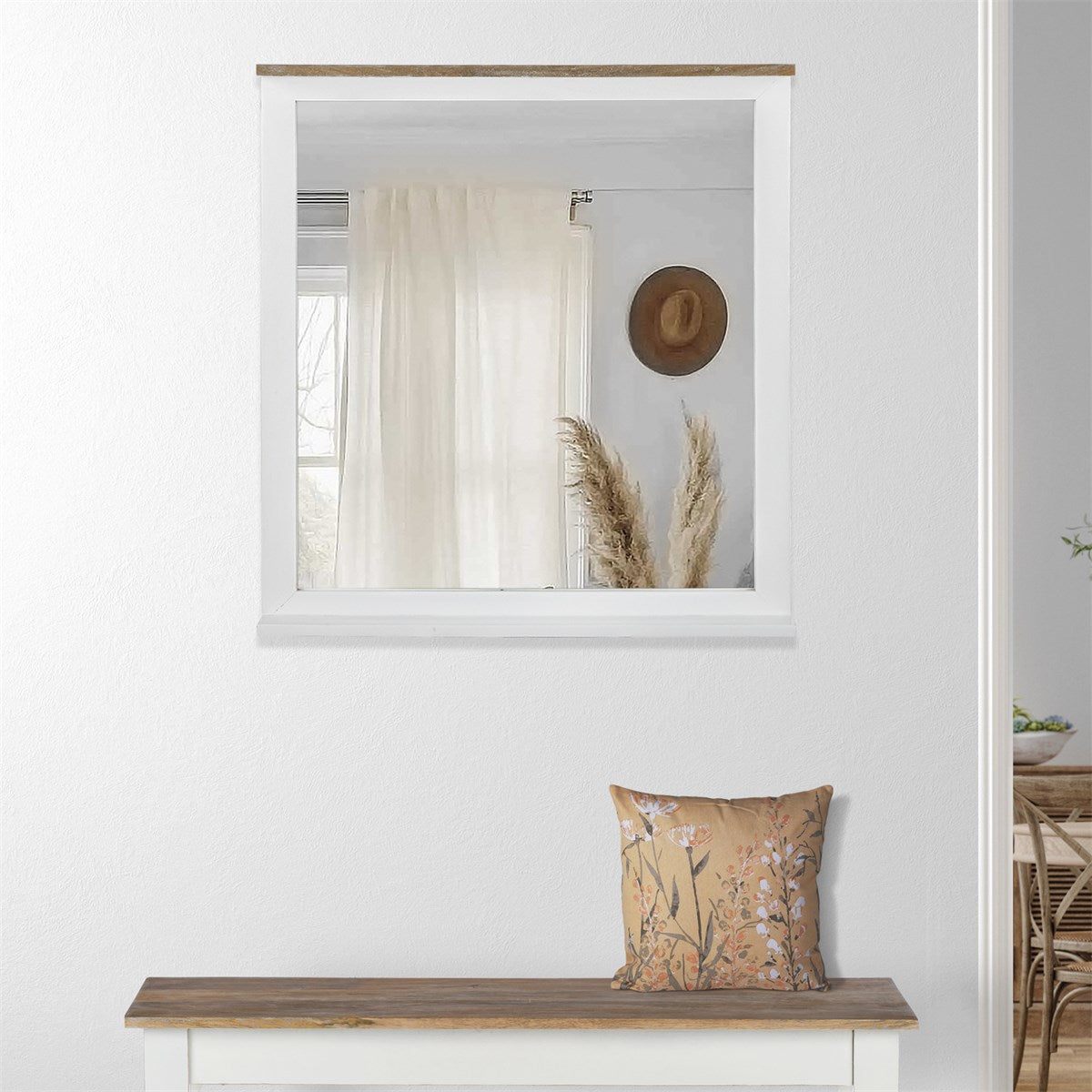 A mirror above a bench with cushions and plants in the background.