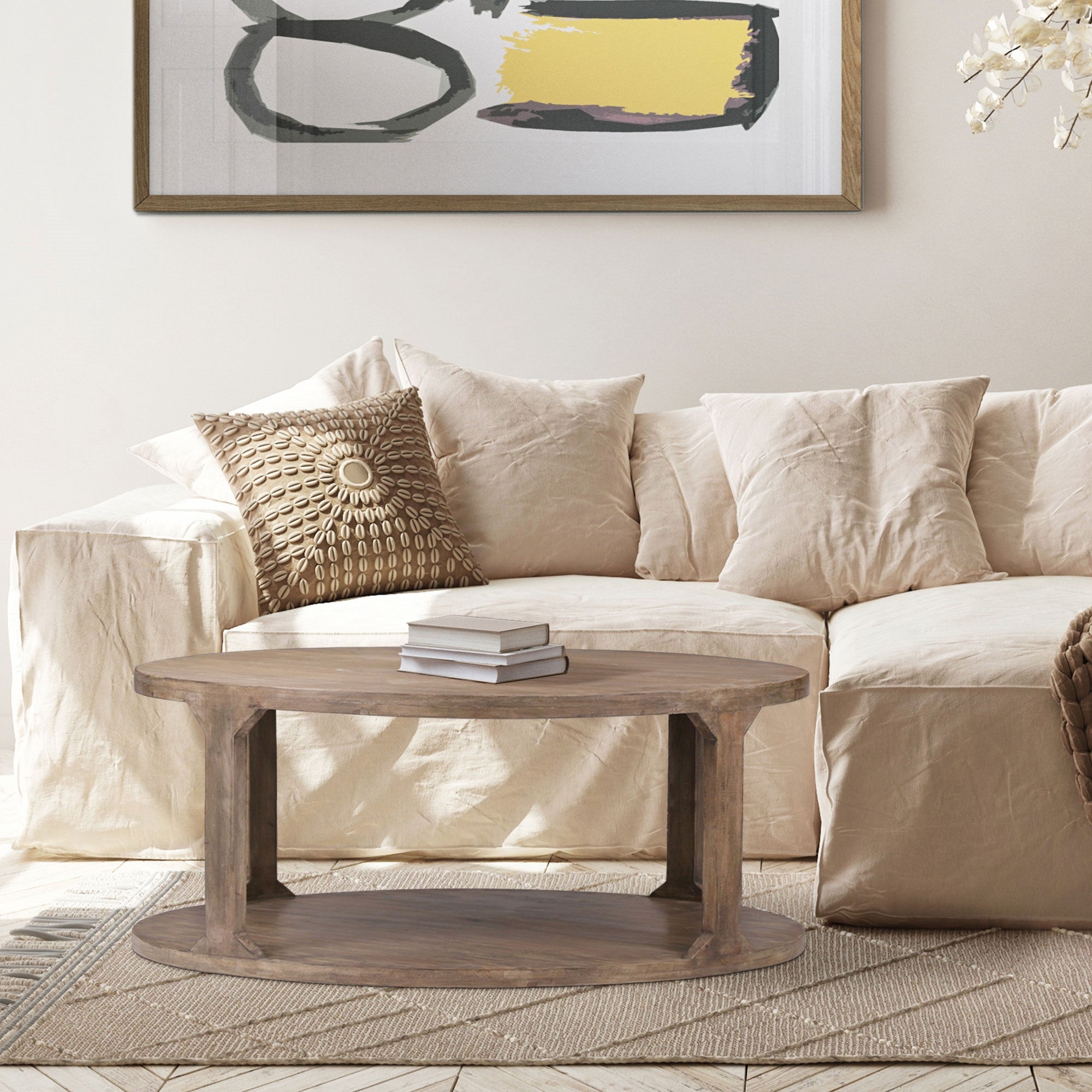 Wohnzimmer mit beigem Sofa, Kissen und einem runden Holztisch.