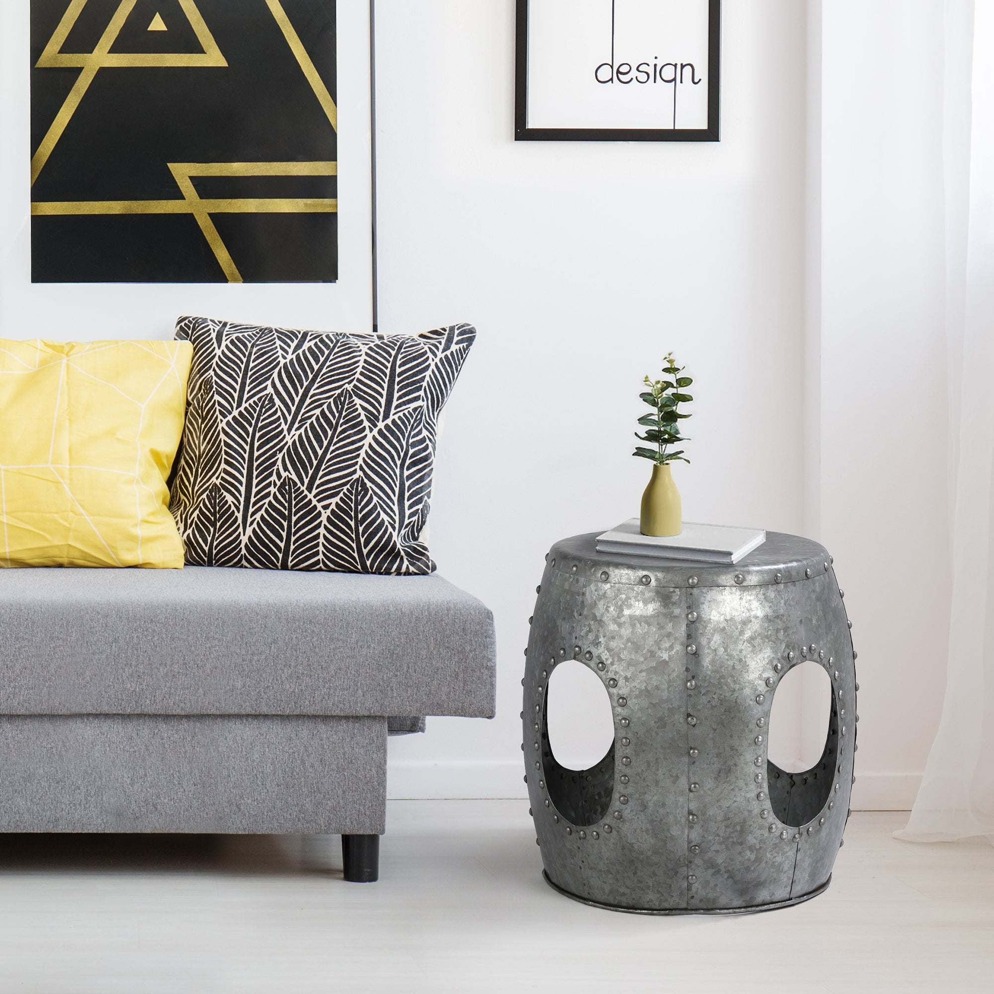 Gråt sofa med puder og sølvfarvet sidebord i et lyst rum.
