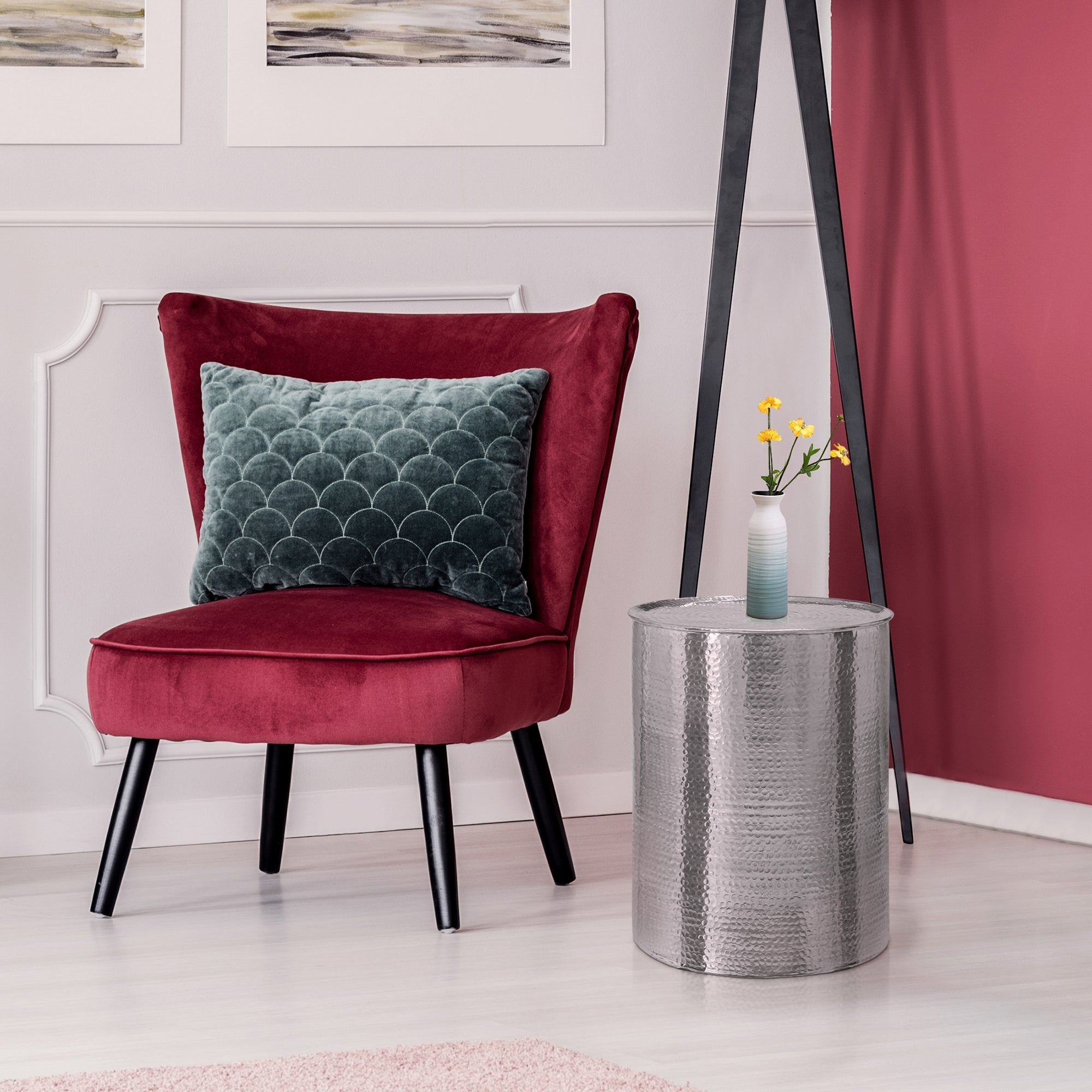 Red armchair with cushions and a silver side table in a modern room.