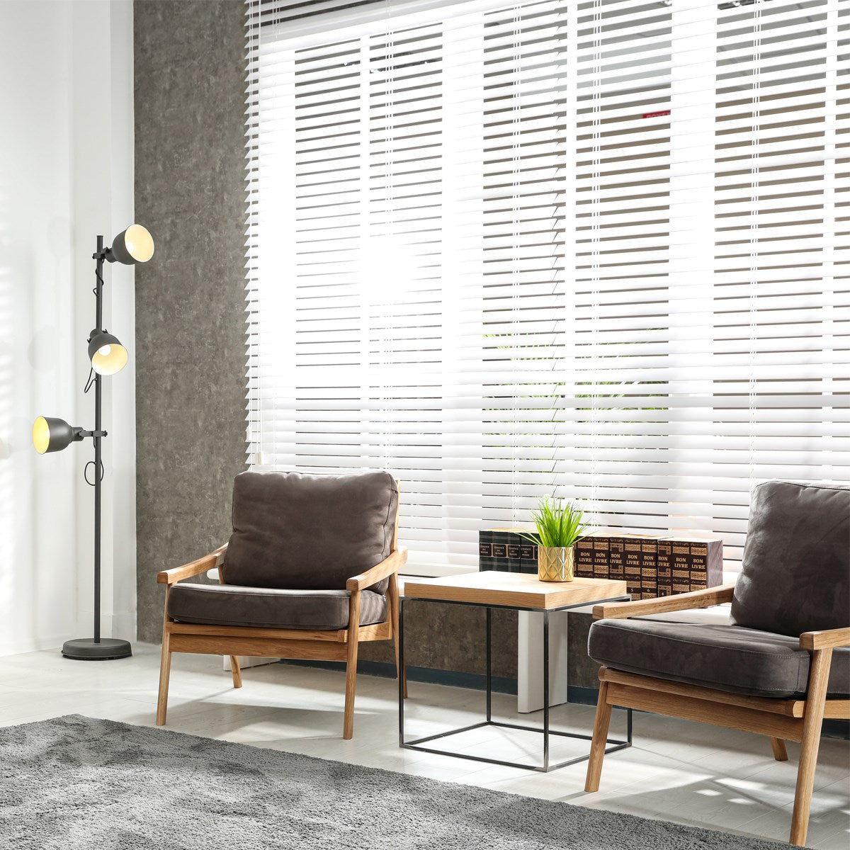 Wohnzimmer mit weißen Jalousien, zwei Sessel und eine Stehlampe.