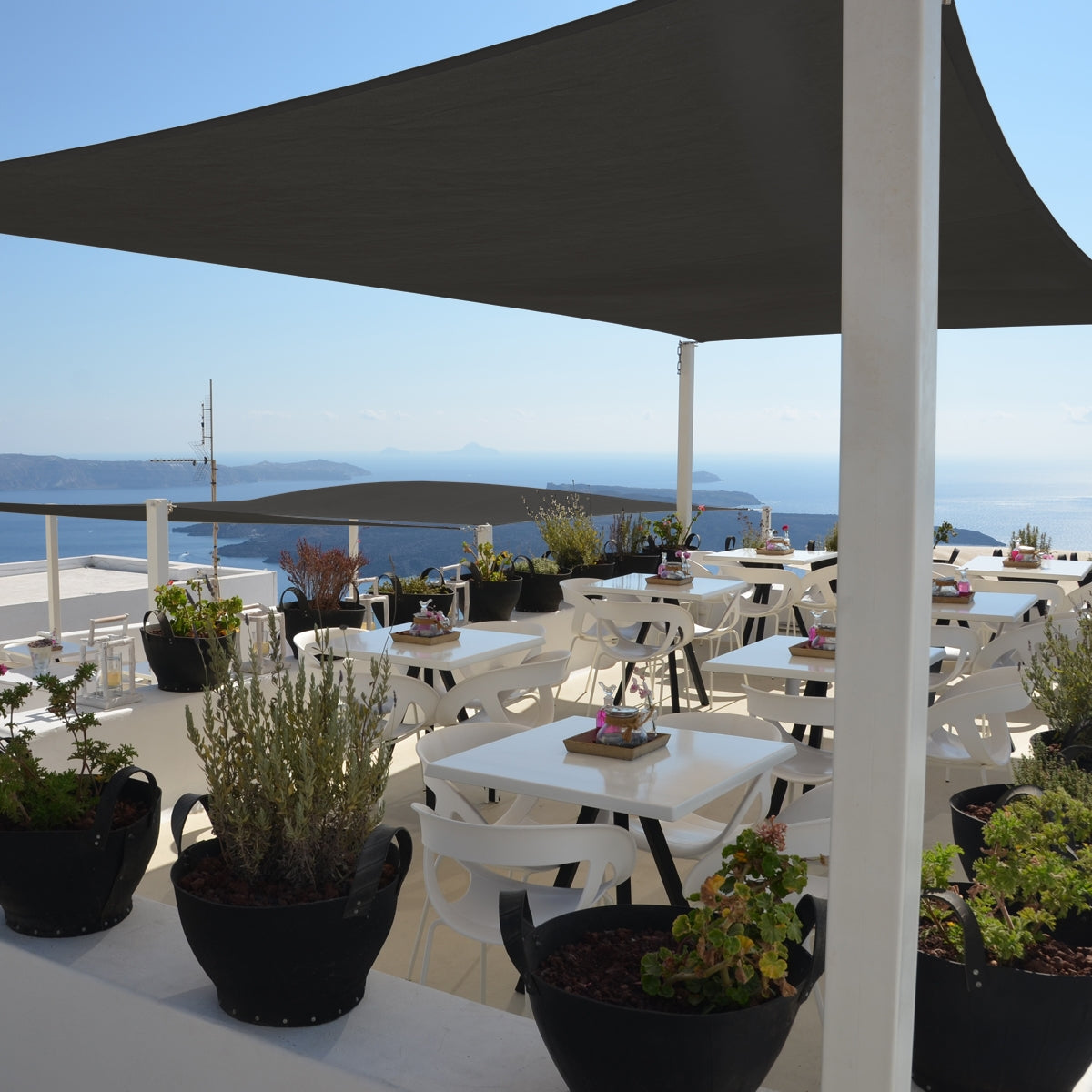 Terraza con mesas, plantas y una gran sombrilla de color antracita.