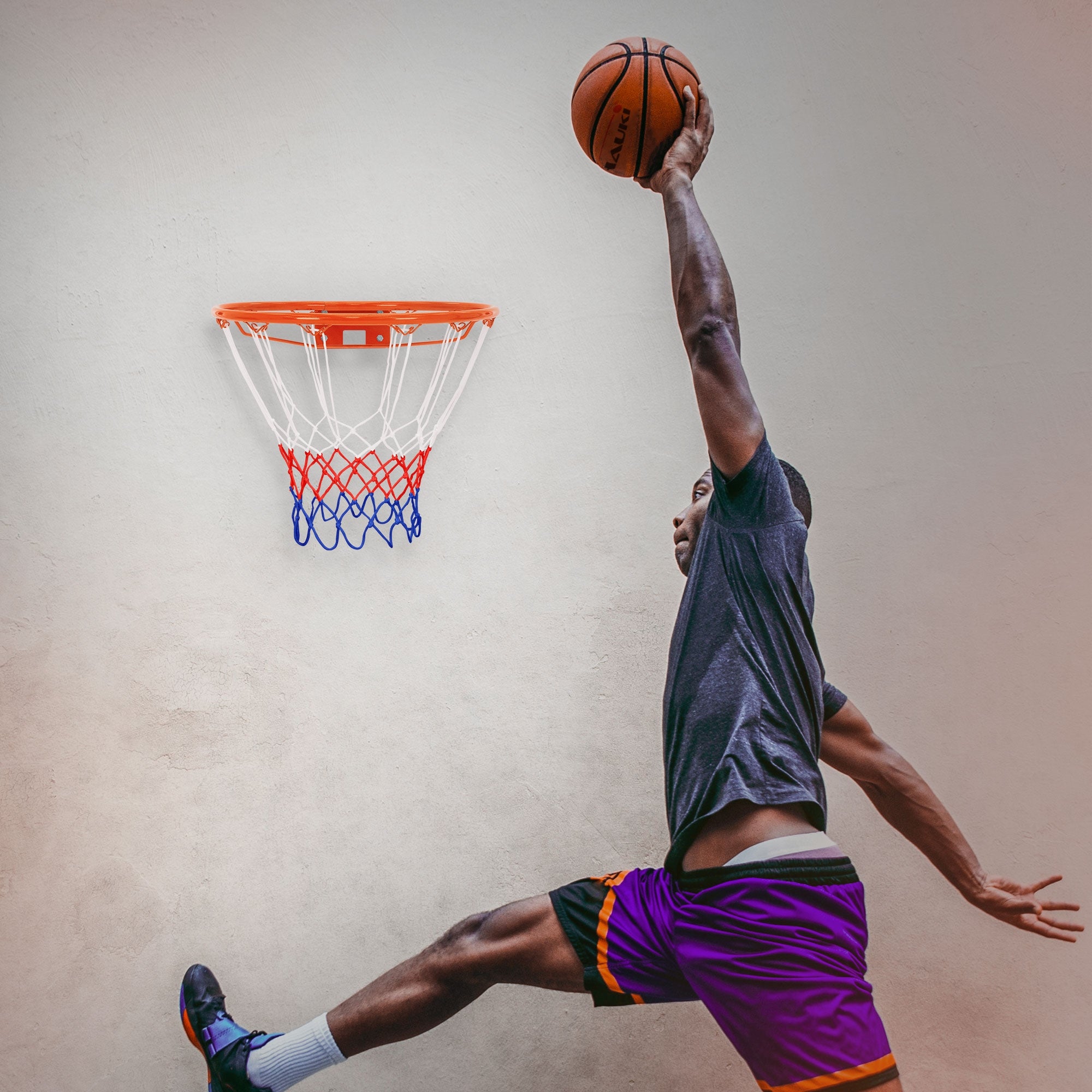 Ein Basketballspieler springt und wirft den Ball in den Korb an einer Wand.