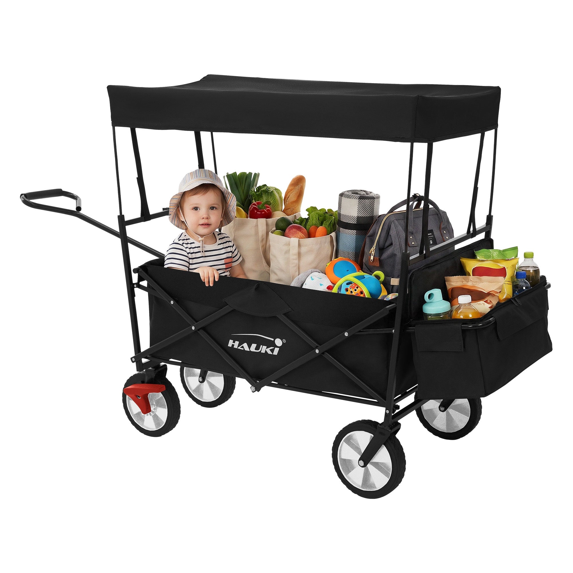 Un enfant est assis dans un chariot noir, entouré de nourriture et de jouets.