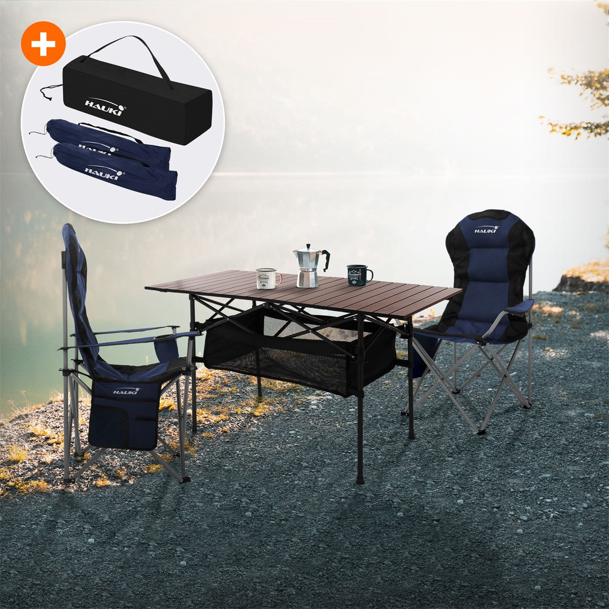 A camping table with two chairs on the shore of a lake, surrounded by trees.