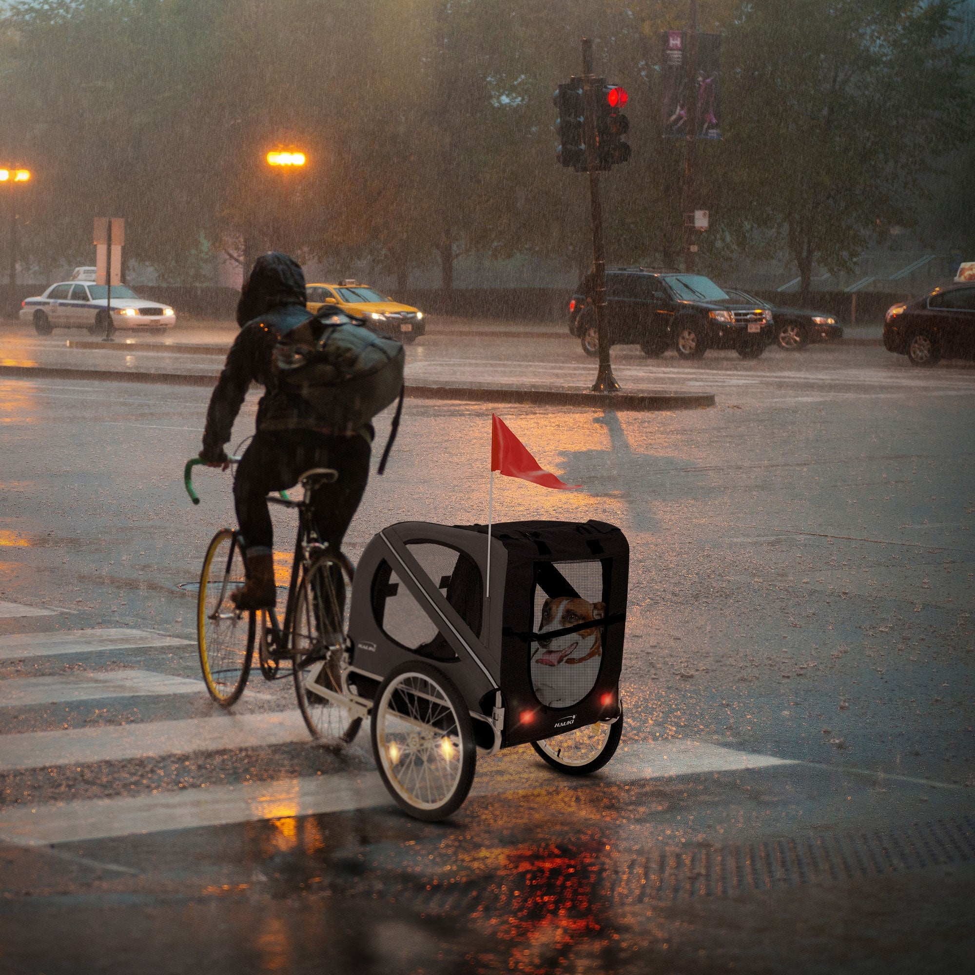 Fahrradfahrer mit Anhänger bei Regen an einer Ampel.