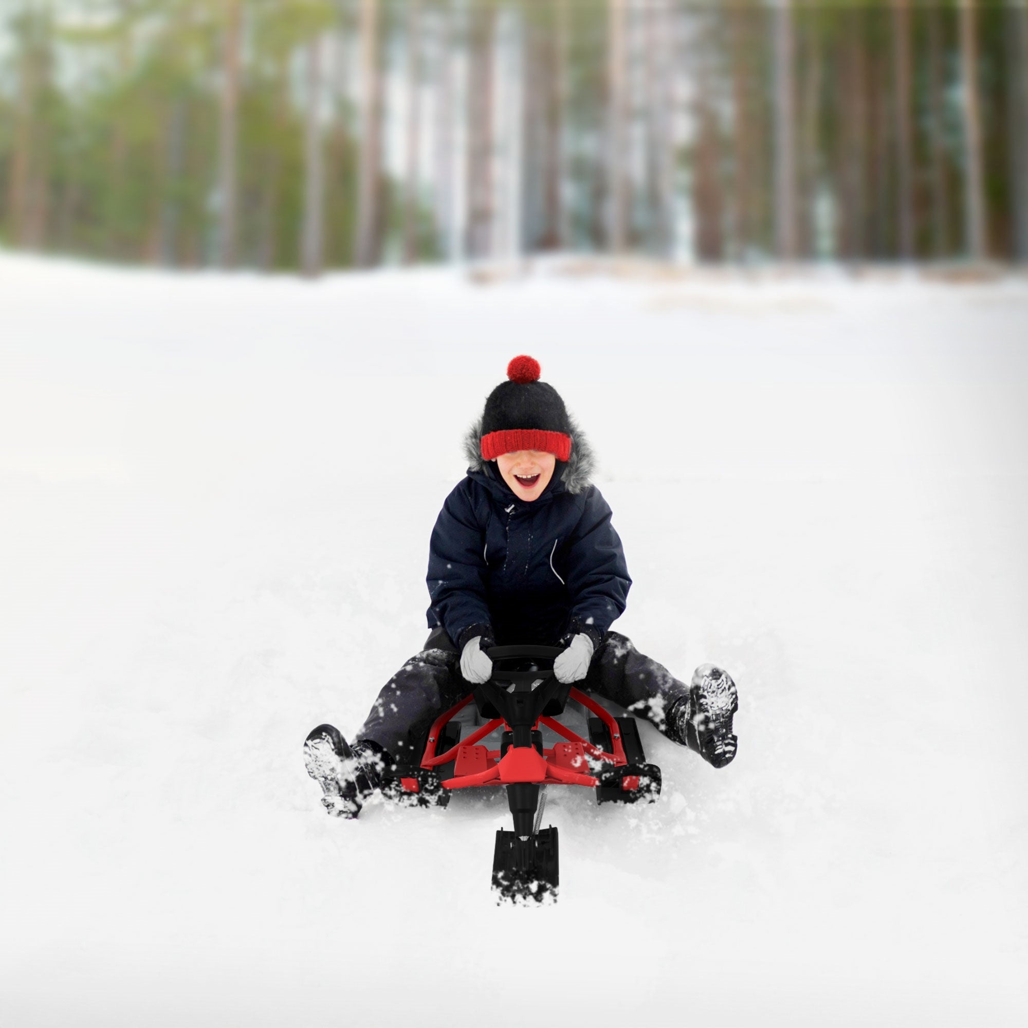 A laughing child on a sled in the snow, surrounded by trees.