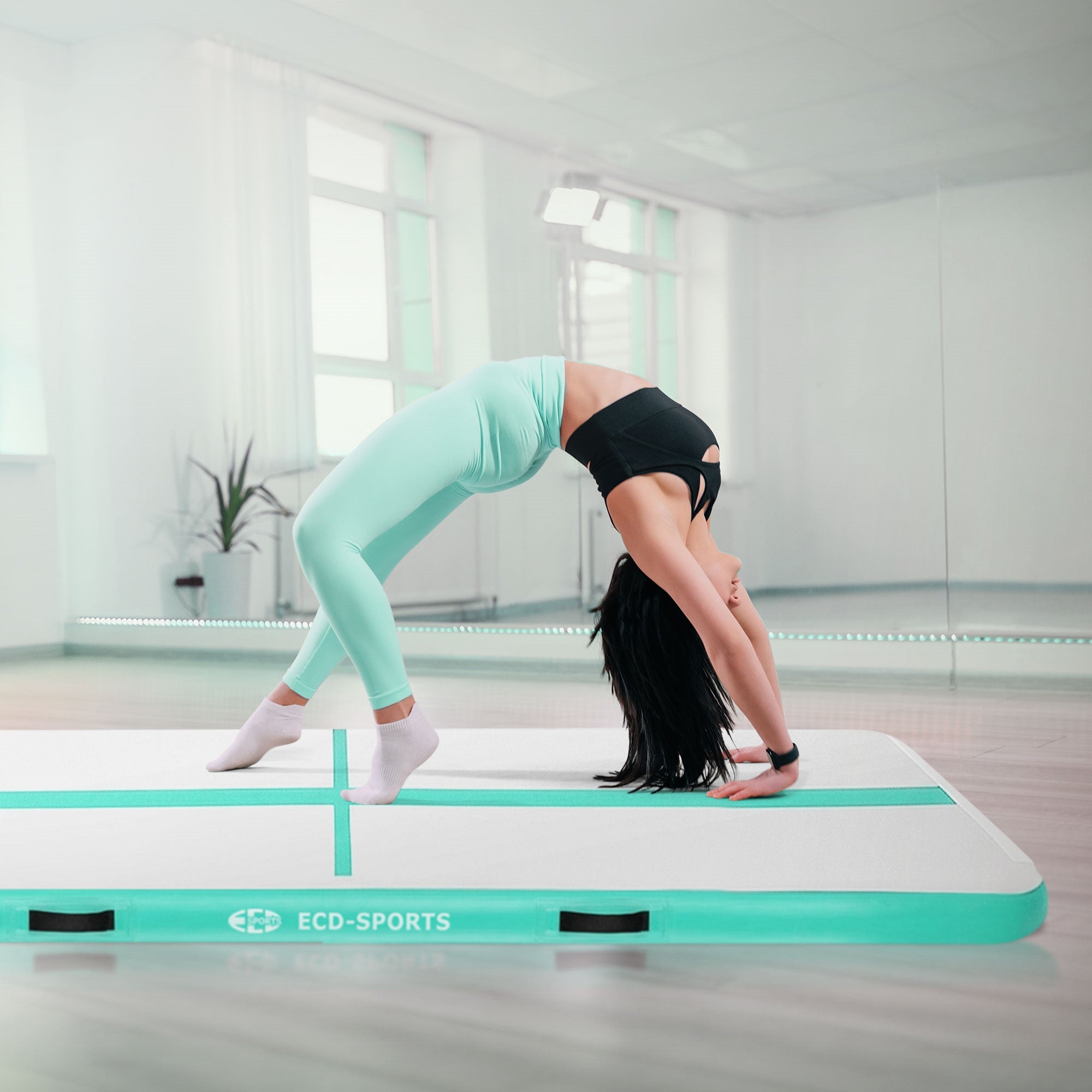 Kvinde i sportstøj udfører en baglæns salto på en gymnastikmåtte.