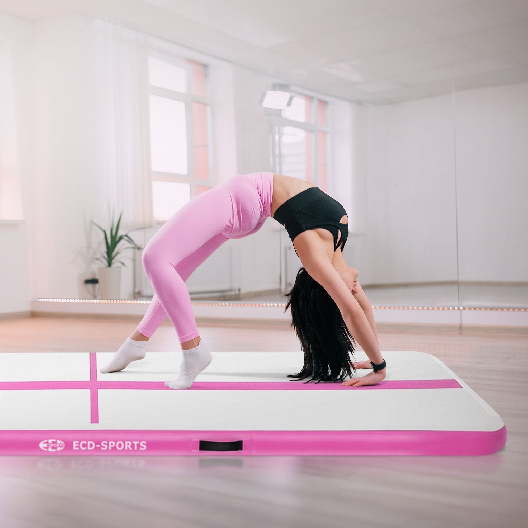 Person in sportlicher Kleidung macht einen Rückwärtsbogen auf einer rosa Gymnastikmatte.