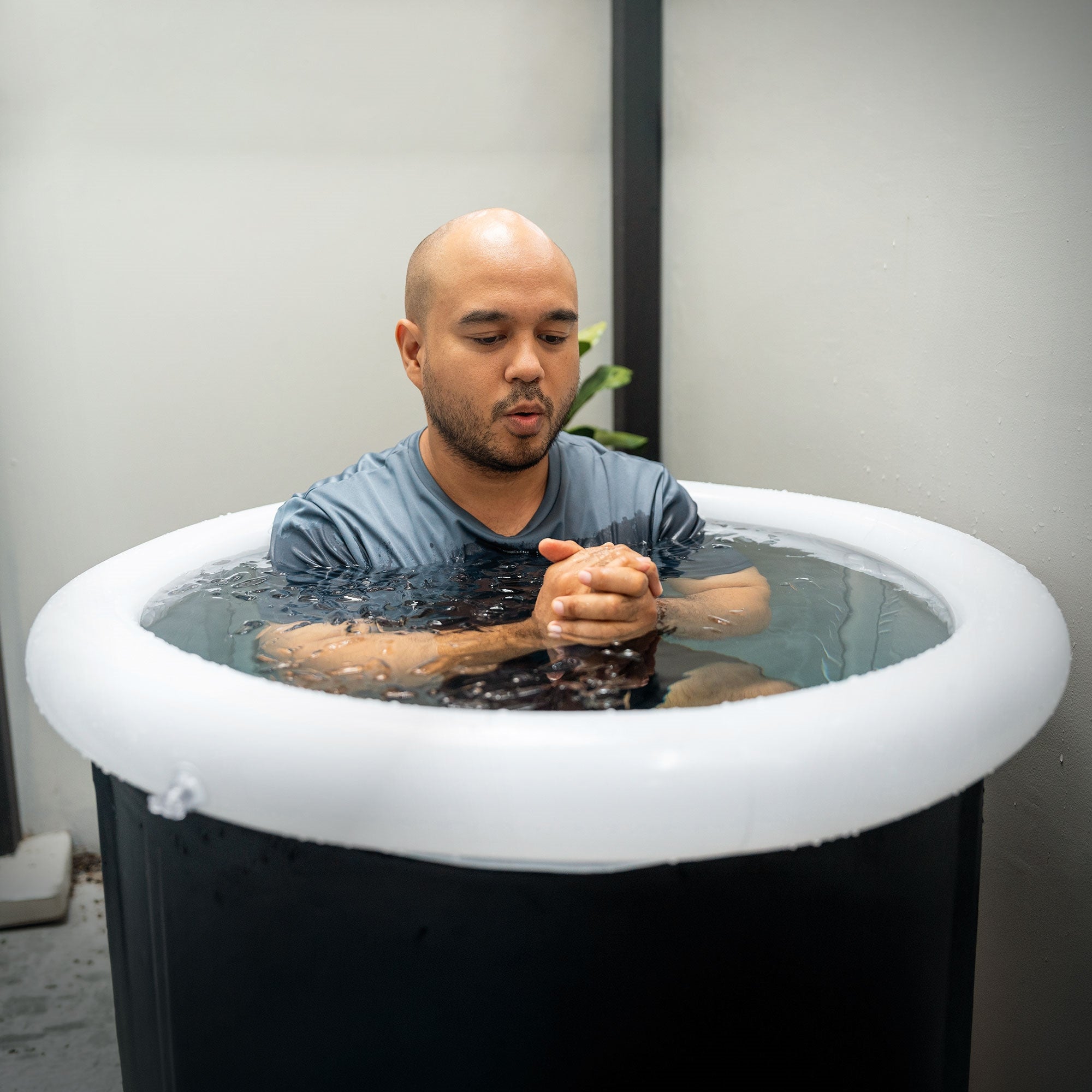 Mann sitzt in einem aufblasbaren Pool mit Wasser.