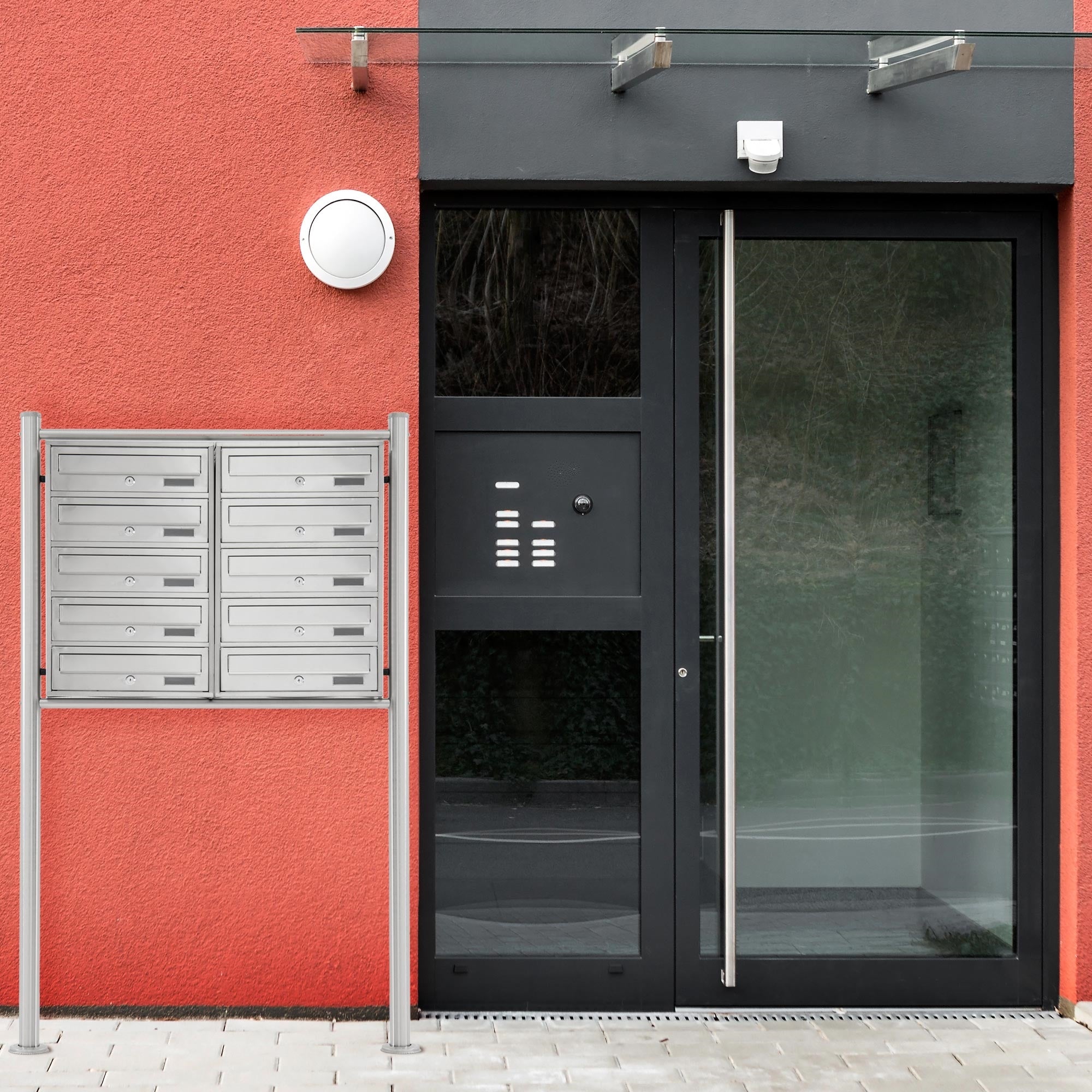 Puerta de entrada con vidrio y buzón plateado al lado.
