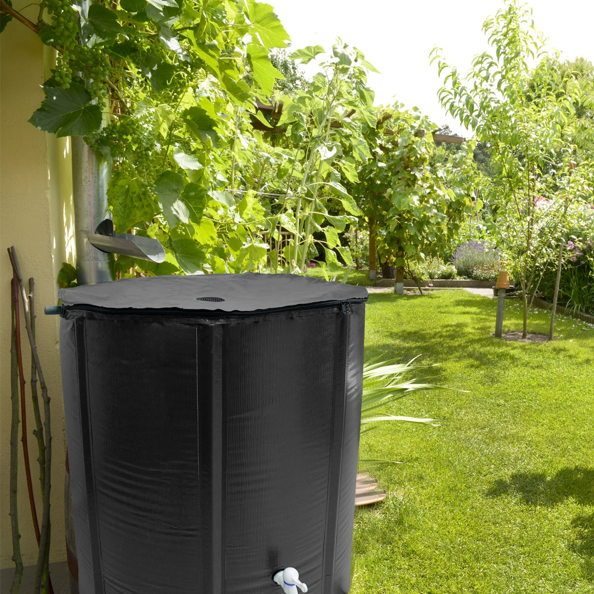 Schwarzer Wassertank im Garten, umgeben von Pflanzen.