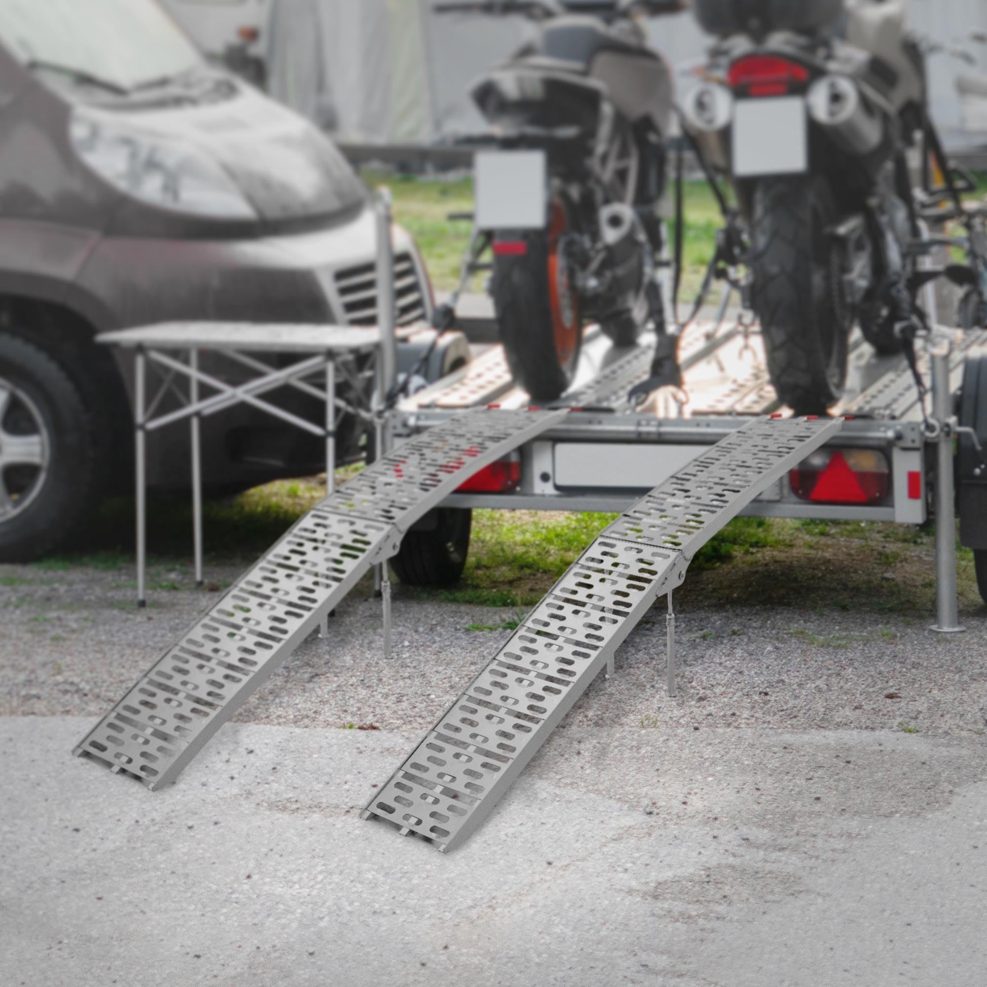 Zwei Motorräder auf einem Anhänger mit zwei Rampen im Vordergrund.