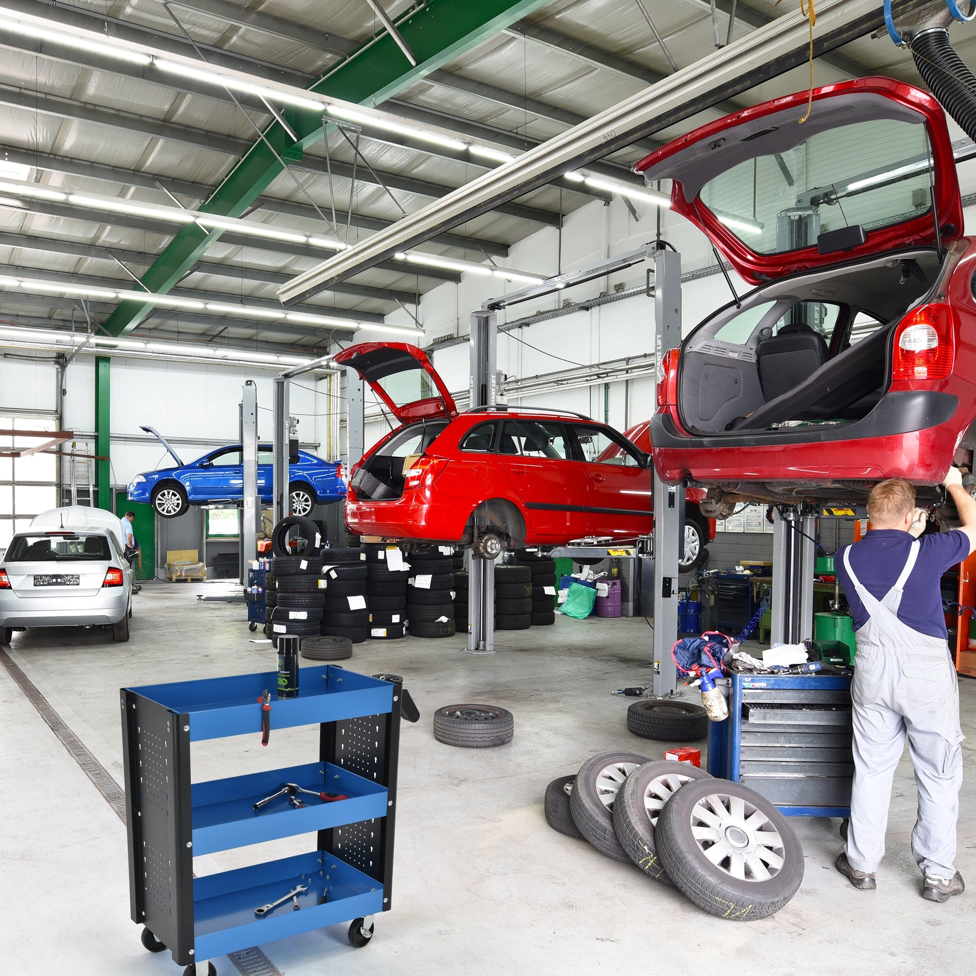 Werkstatt mit Autos auf Hebebühnen und einem blauen Werkstattwagen.