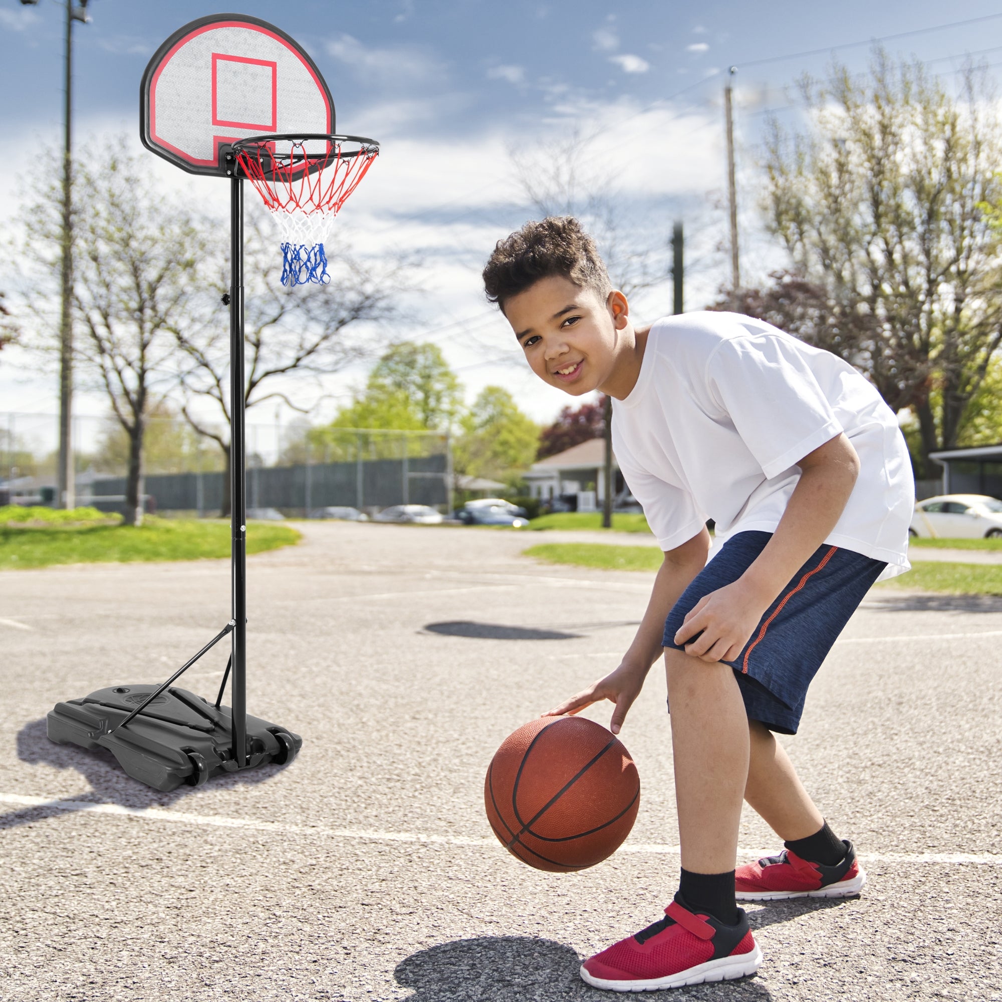 Boy with a basketball in front of a basketball hoop on a sports field.