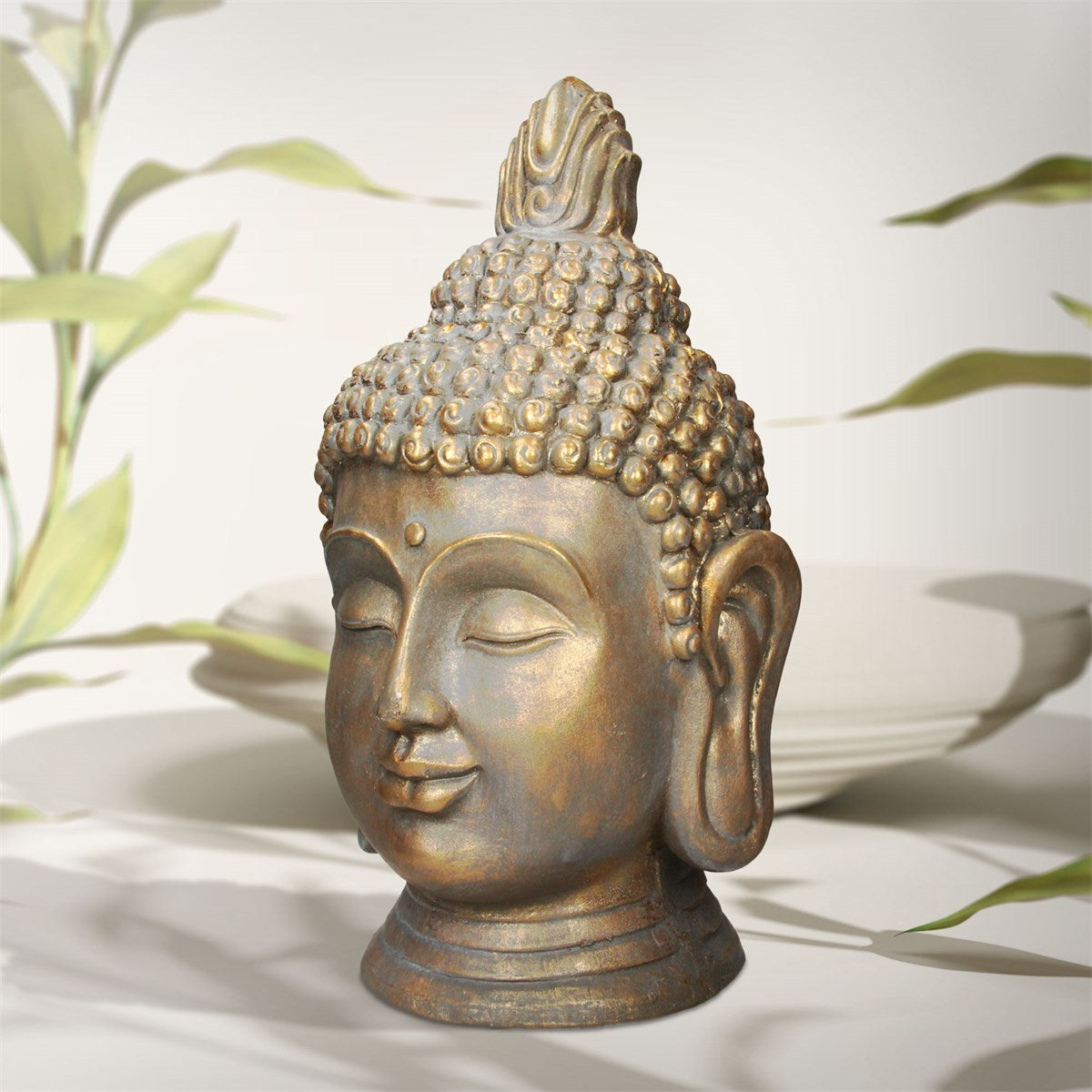 Buddha-Kopf aus Stein mit geschlossenen Augen, vor einem hellen Hintergrund.