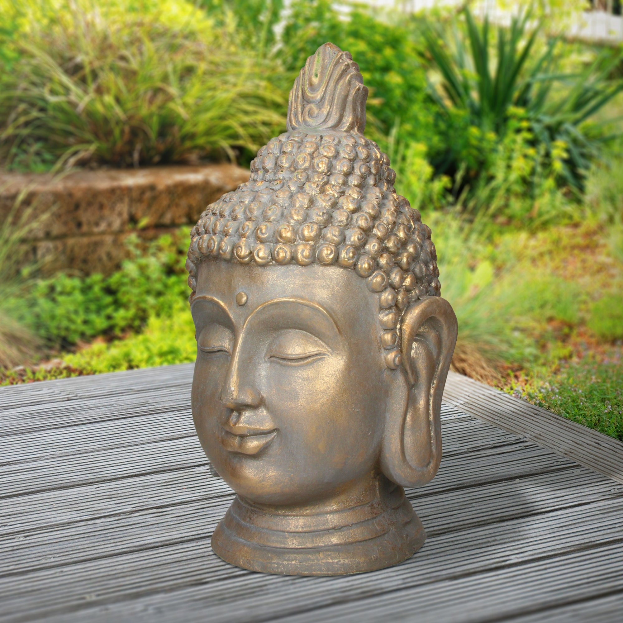 Buddha-Kopf aus Stein mit lächelndem Gesicht, auf einem Holztisch im Freien.