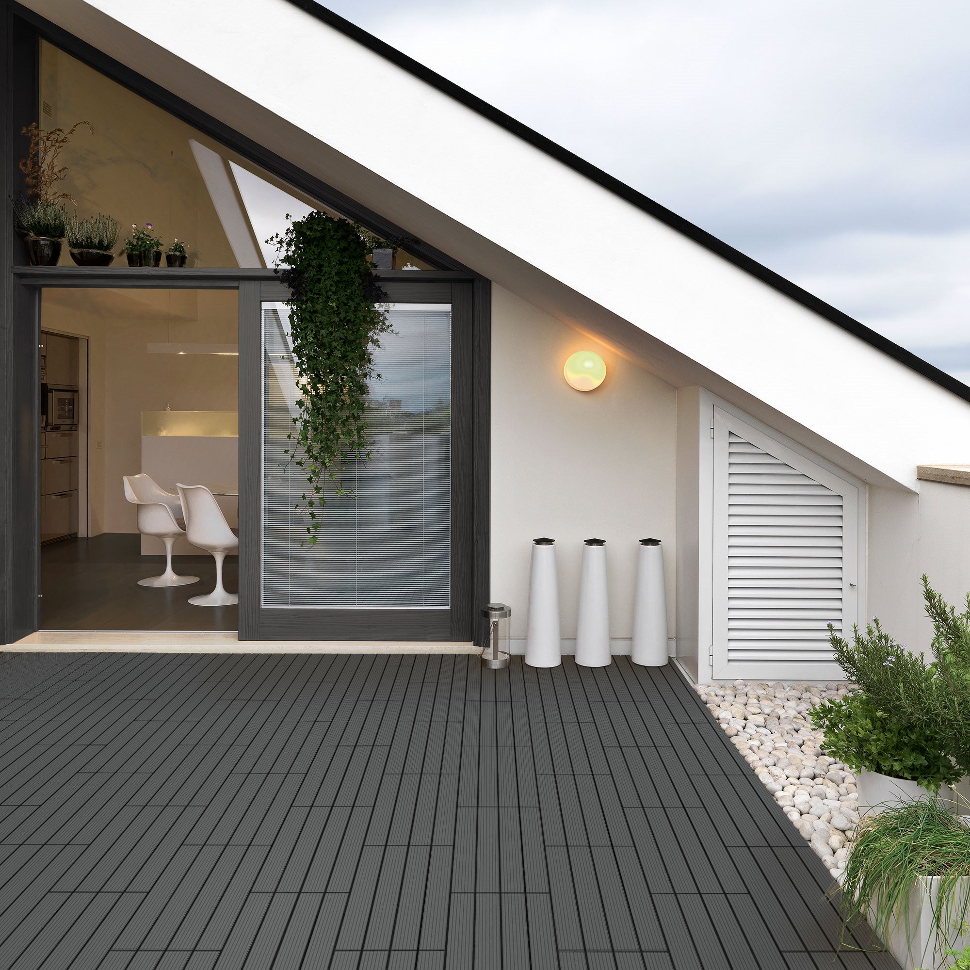Moderne Terrasse mit WPC-Fliesen, Pflanzen und Möbeln im Hintergrund.