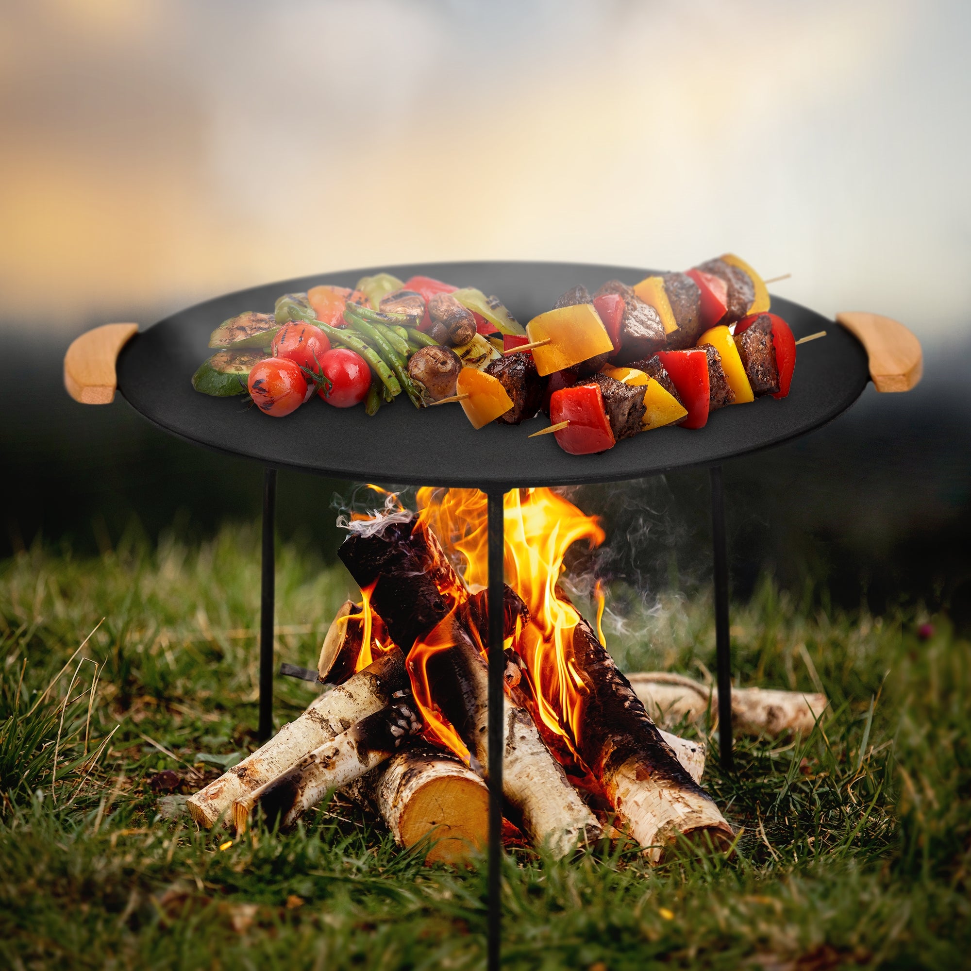 A grill with vegetables and meat skewers on an outdoor fire pit.