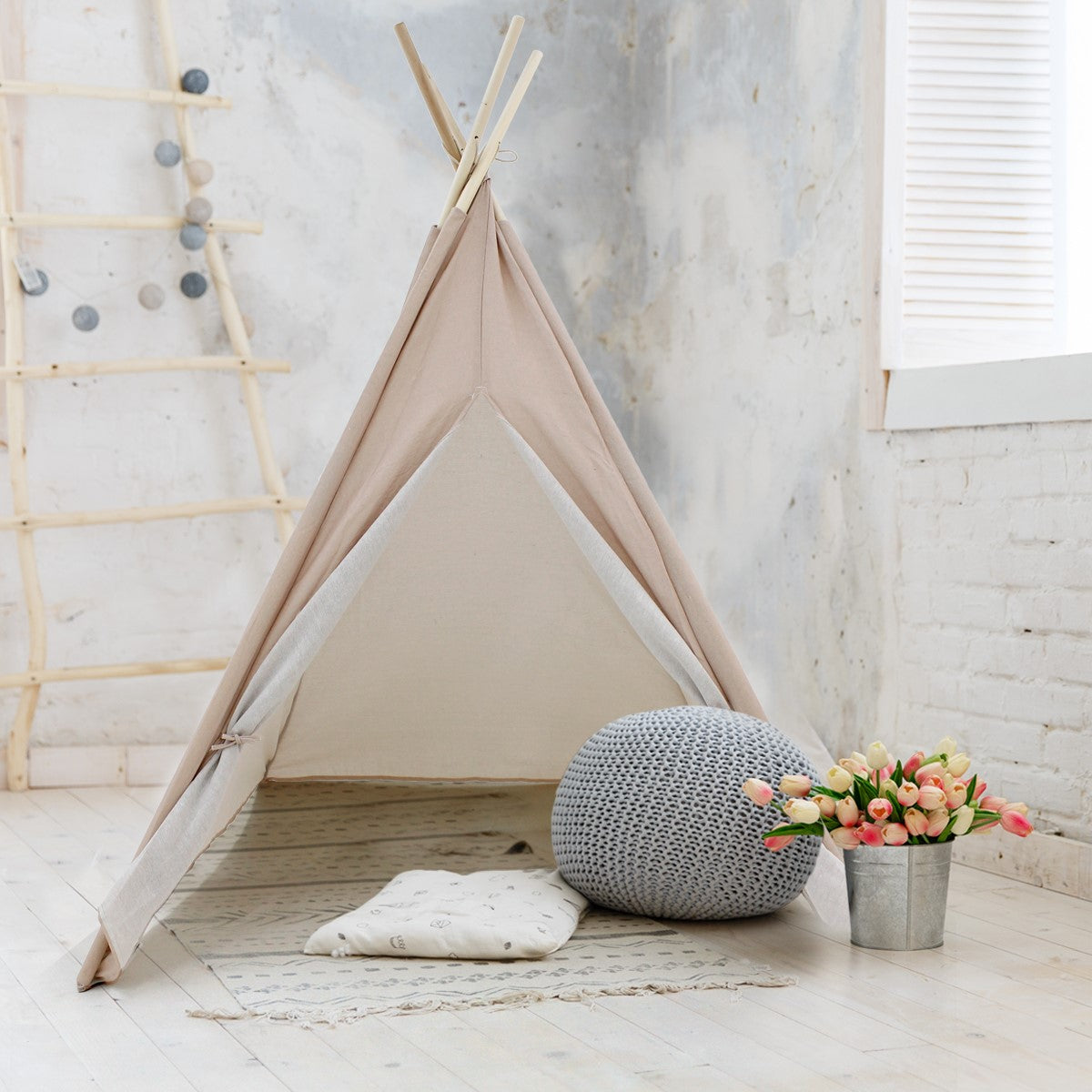 Stan ve tvaru teepee s polštářem a květinami.