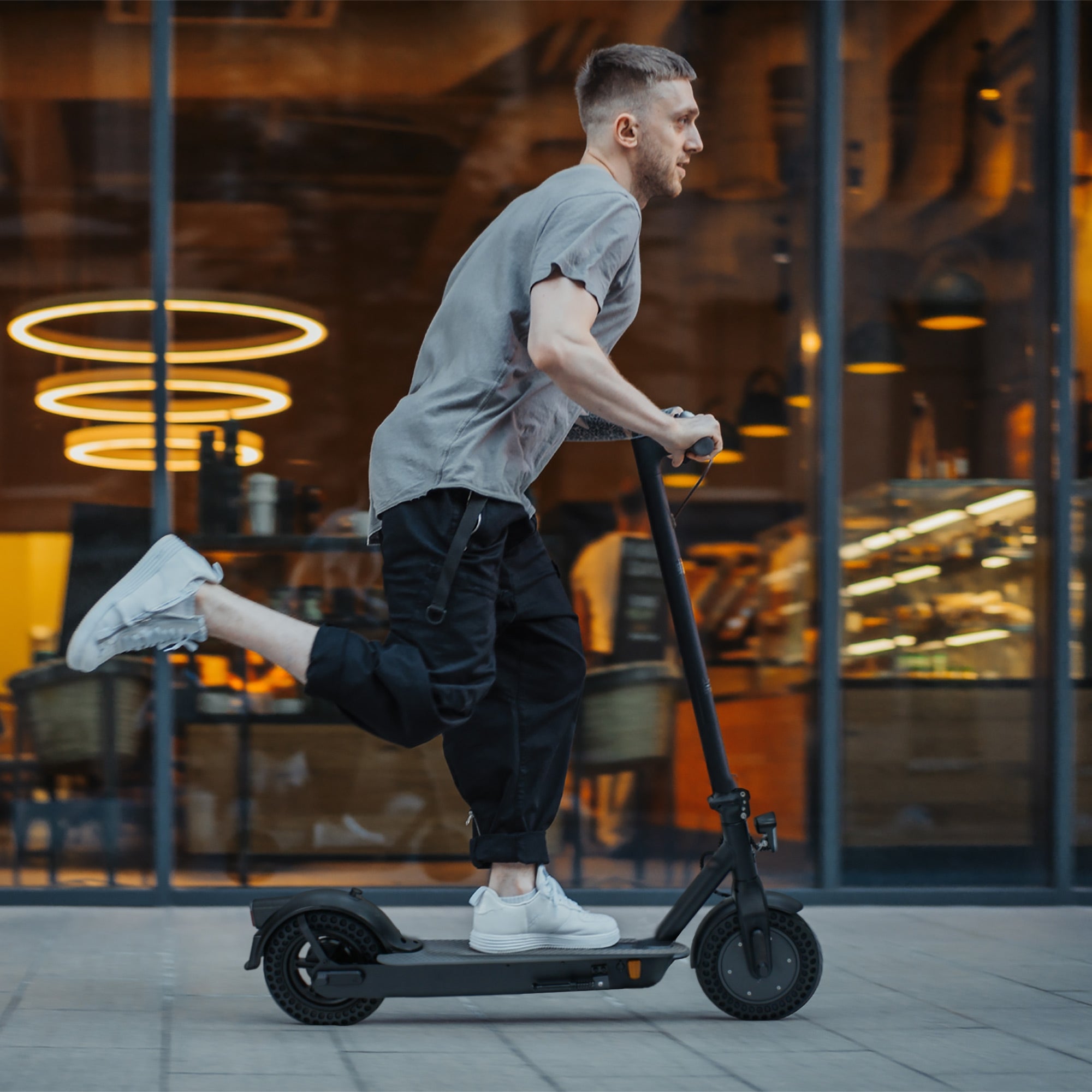 Hombre montando un patinete eléctrico en un entorno urbano.