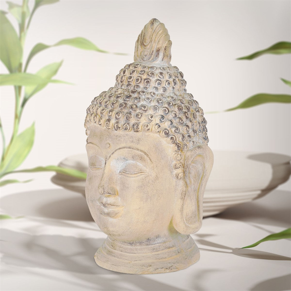 Buddha-Statue auf einem Tisch mit Pflanzen im Hintergrund.